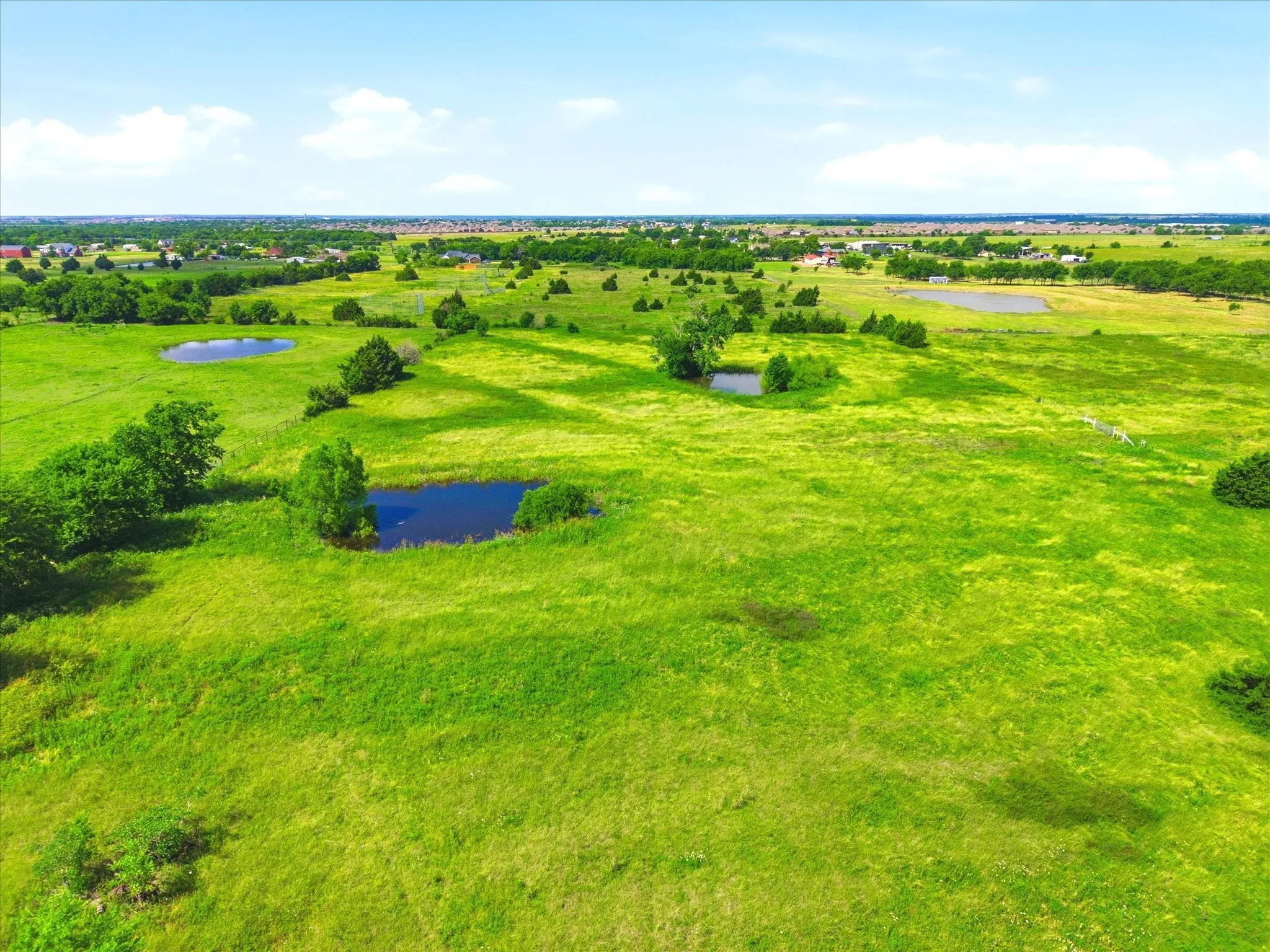 Expansive green landscape featuring multiple ponds and scattered mature trees