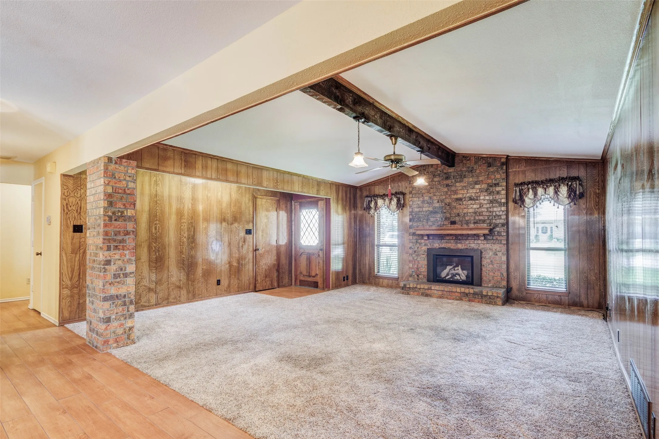 Spacious living area featuring a brick fireplace with a wood mantel