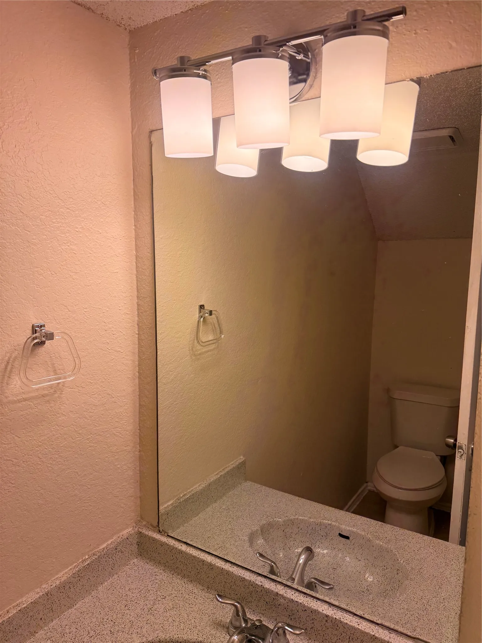 Bathroom vanity featuring a speckled countertop, integrated sink, and a large wall-mounted mirror