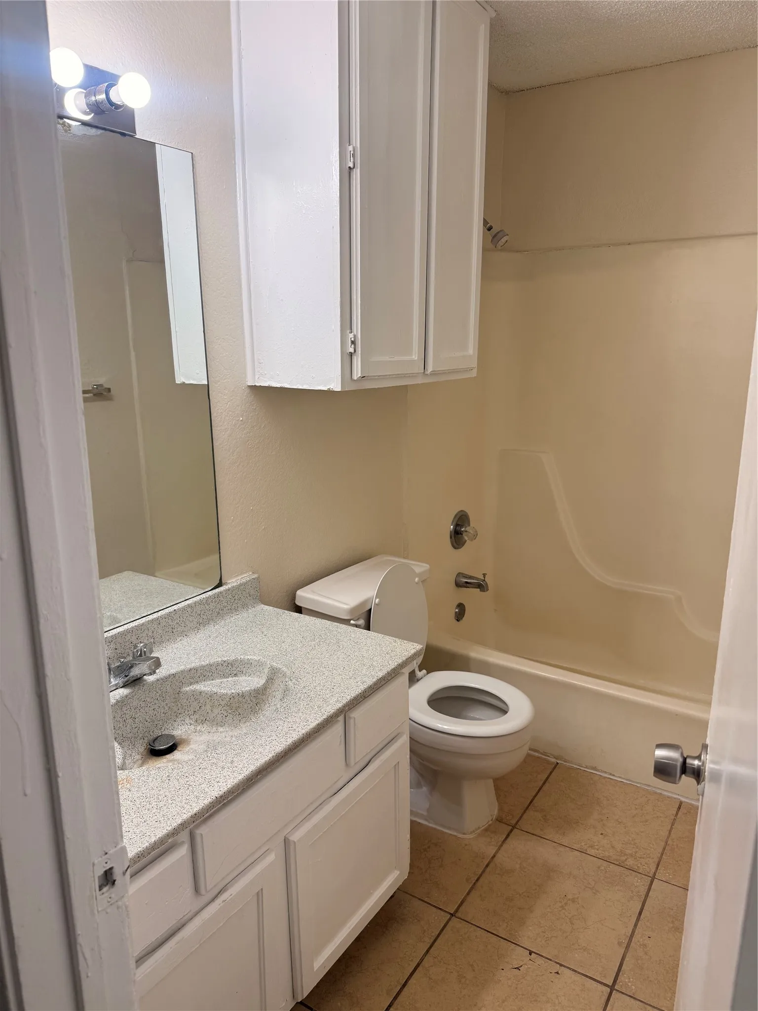 Bathroom featuring a white vanity with an integrated sink, speckled countertop, and chrome faucet