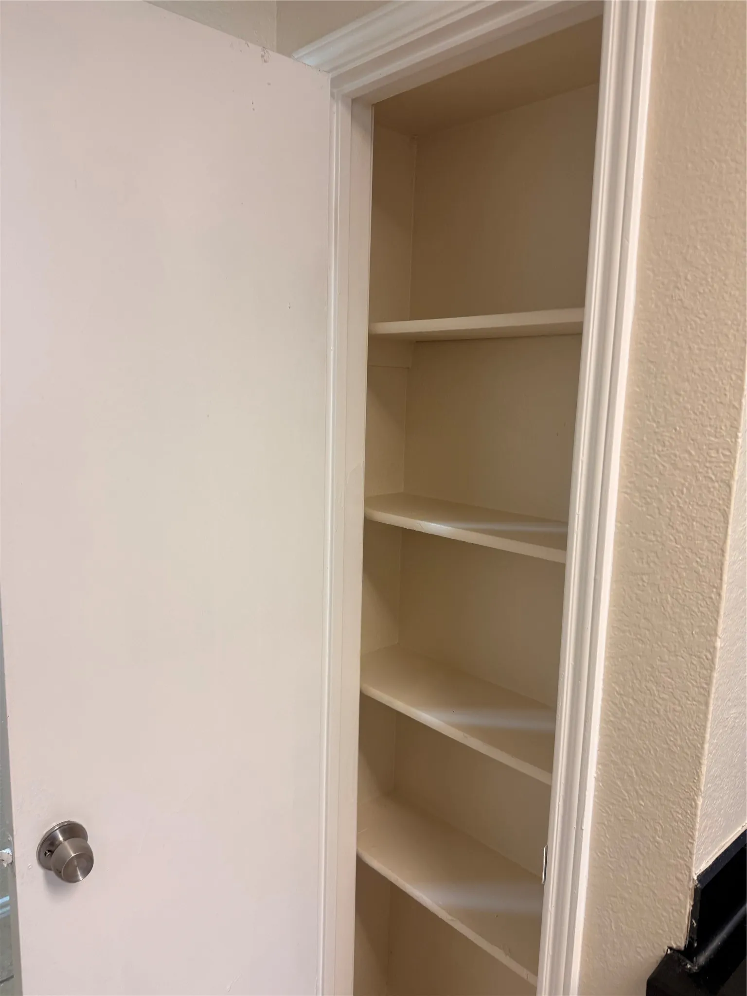 Built-in shelving unit with multiple shelves, recessed within a wall, featuring white trim work