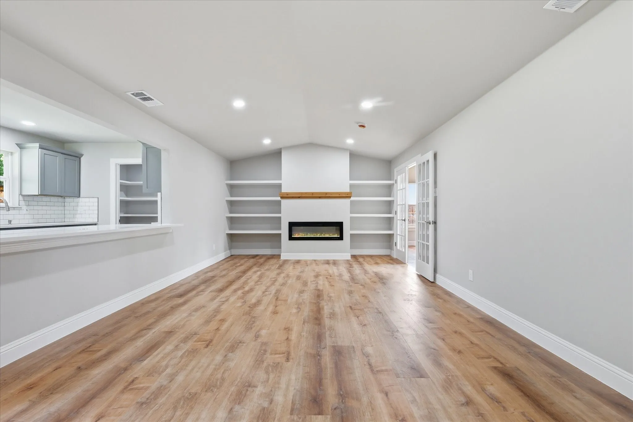 Spacious living area featuring wood-finish flooring, a vaulted ceiling, and recessed lighting