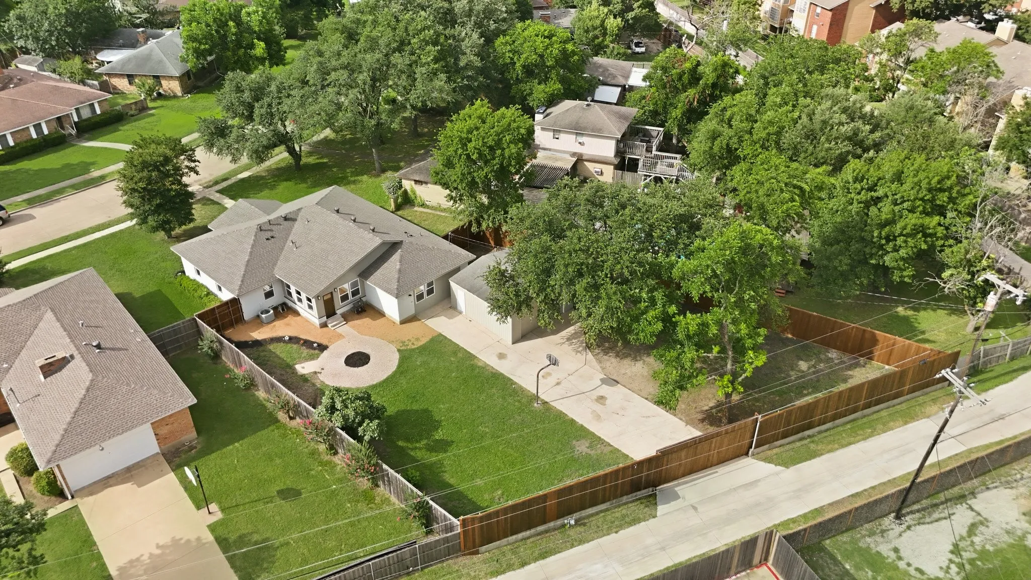 Residential property featuring a spacious backyard, wood privacy fencing, and mature trees