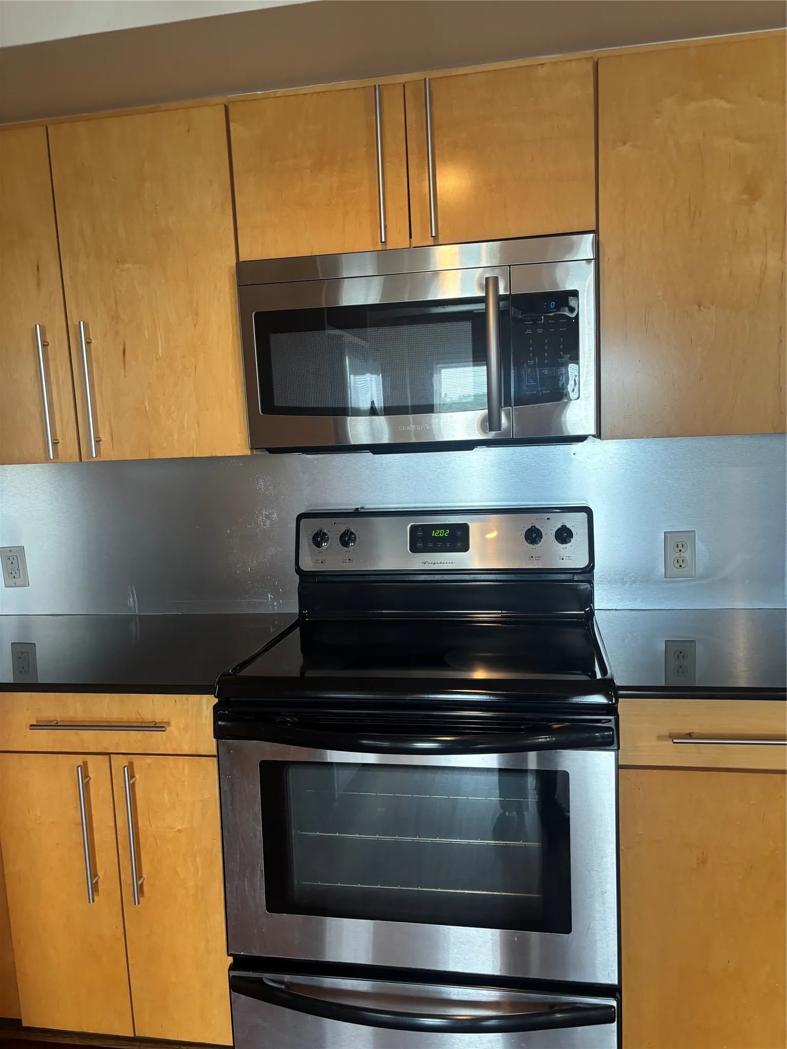 Stainless steel appliance suite featuring an over-the-range microwave and electric range