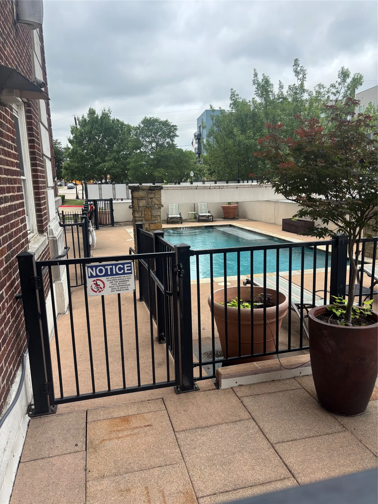 Tiled patio with black iron fencing surrounding a swimming pool