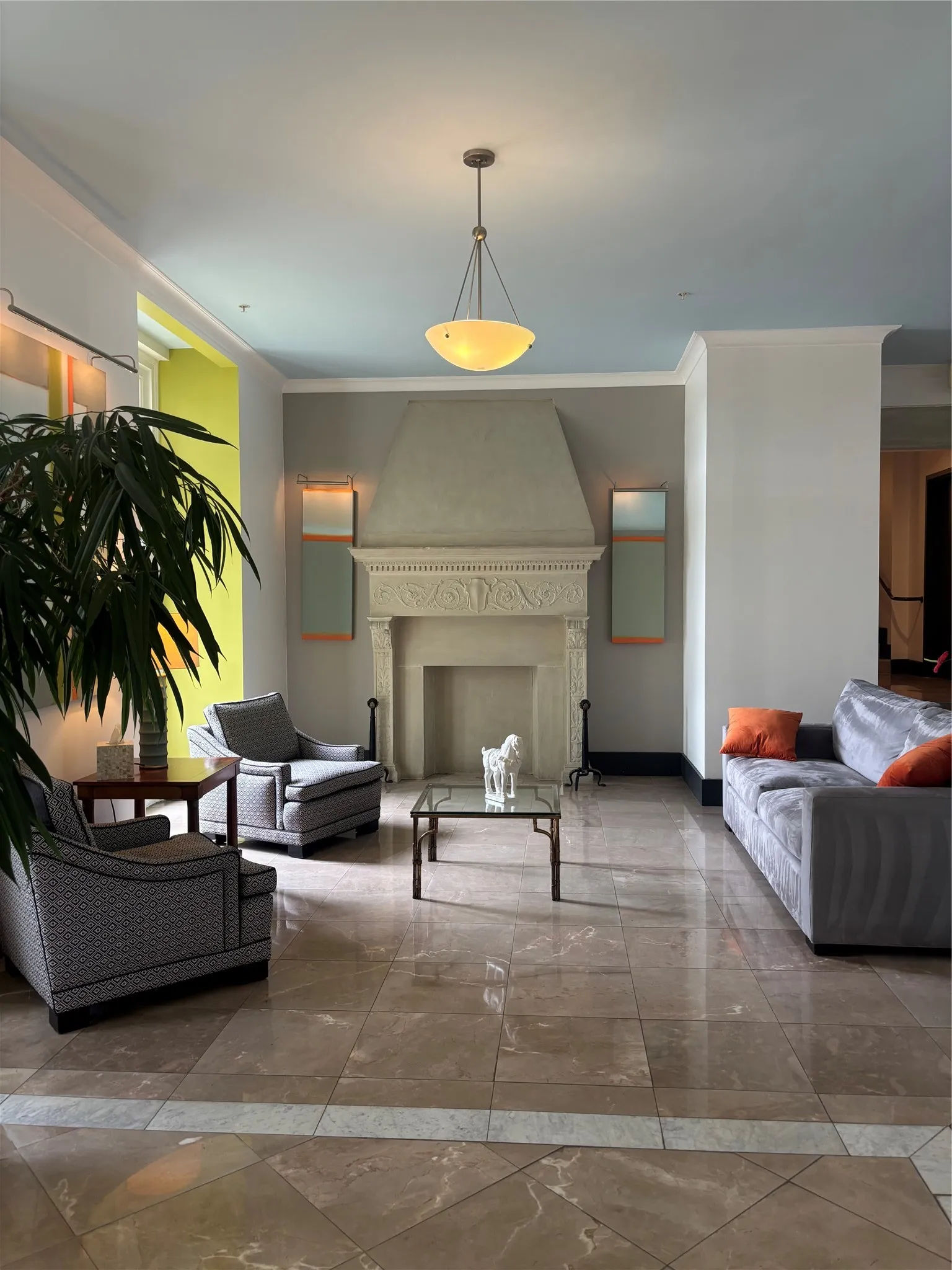 Spacious interior featuring a decorative fireplace with an ornate mantel, polished tile flooring with contrasting accents, and a pendant light fixture
