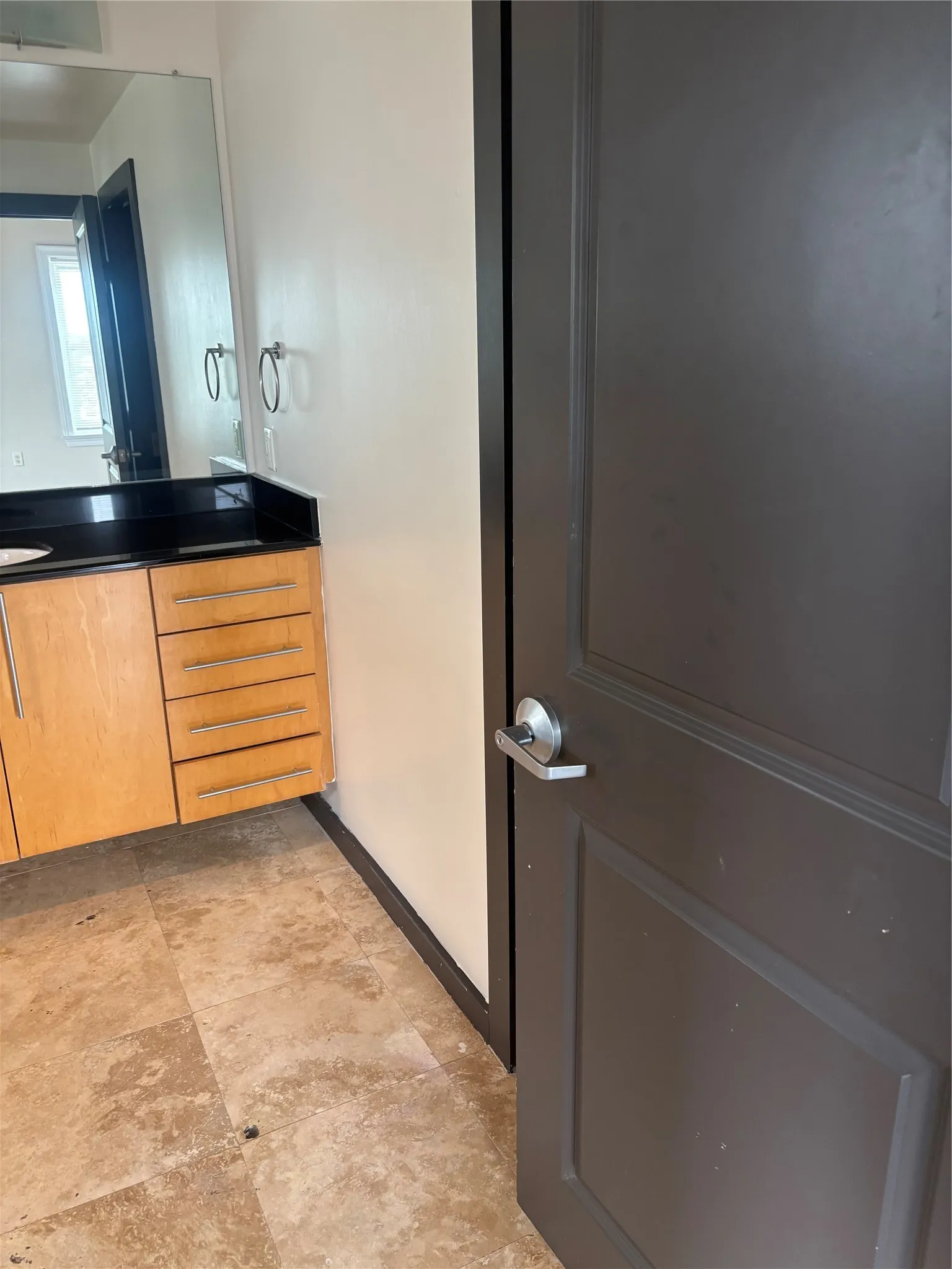 Bathroom vanity featuring a dark countertop and light wood-finish cabinetry