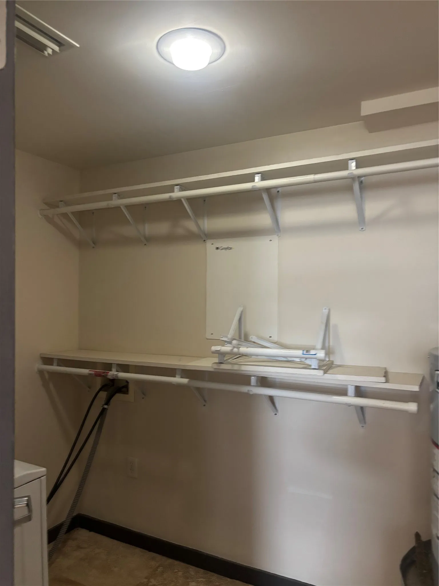 Utility area featuring a ceiling-mounted light fixture, white wire shelving, a white countertop, and tan floor tiles