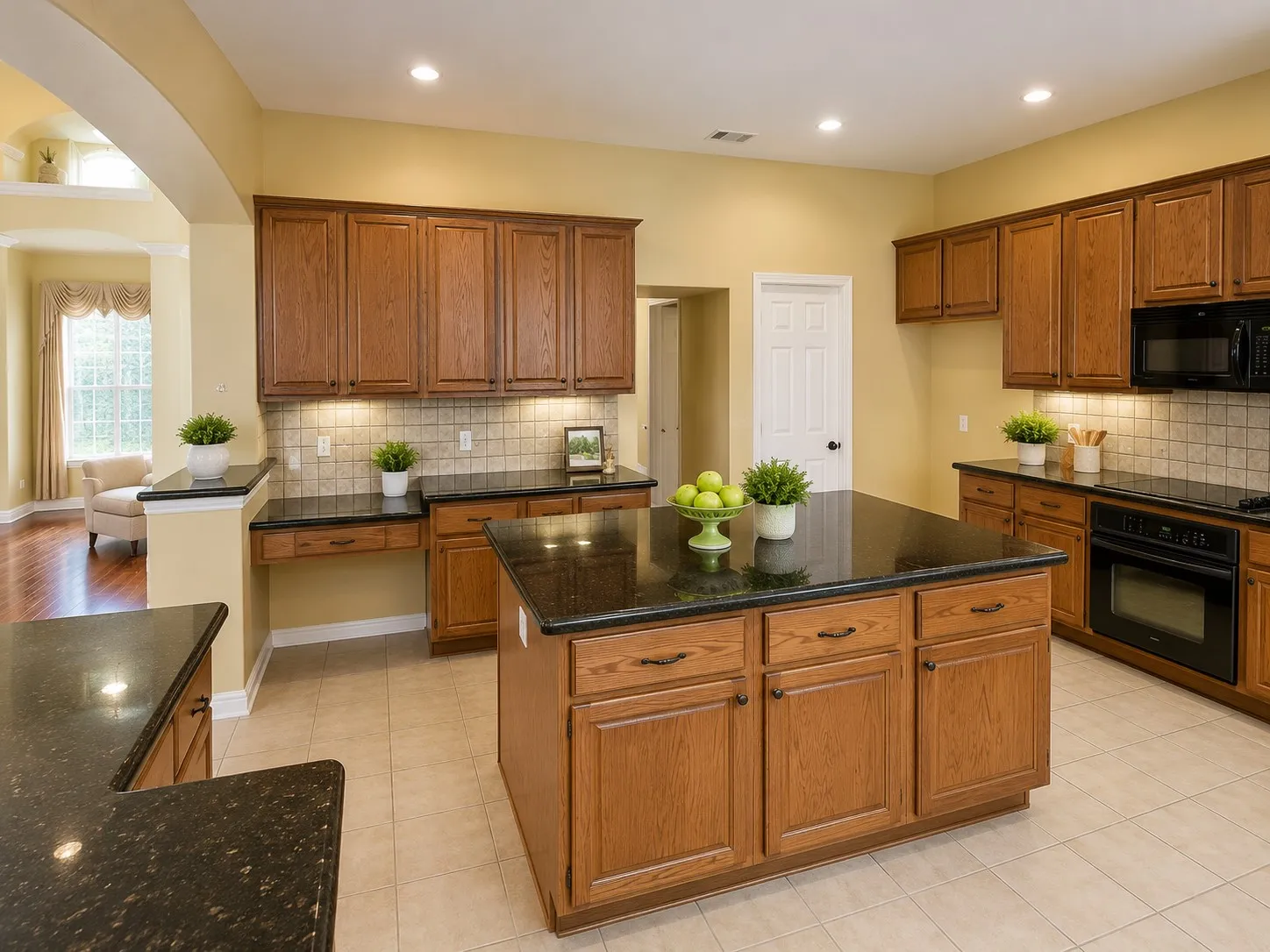 Kitchen featuring a central island with countertop, extensive wood cabinetry, dark countertops, built-in black appliances, and tile flooring