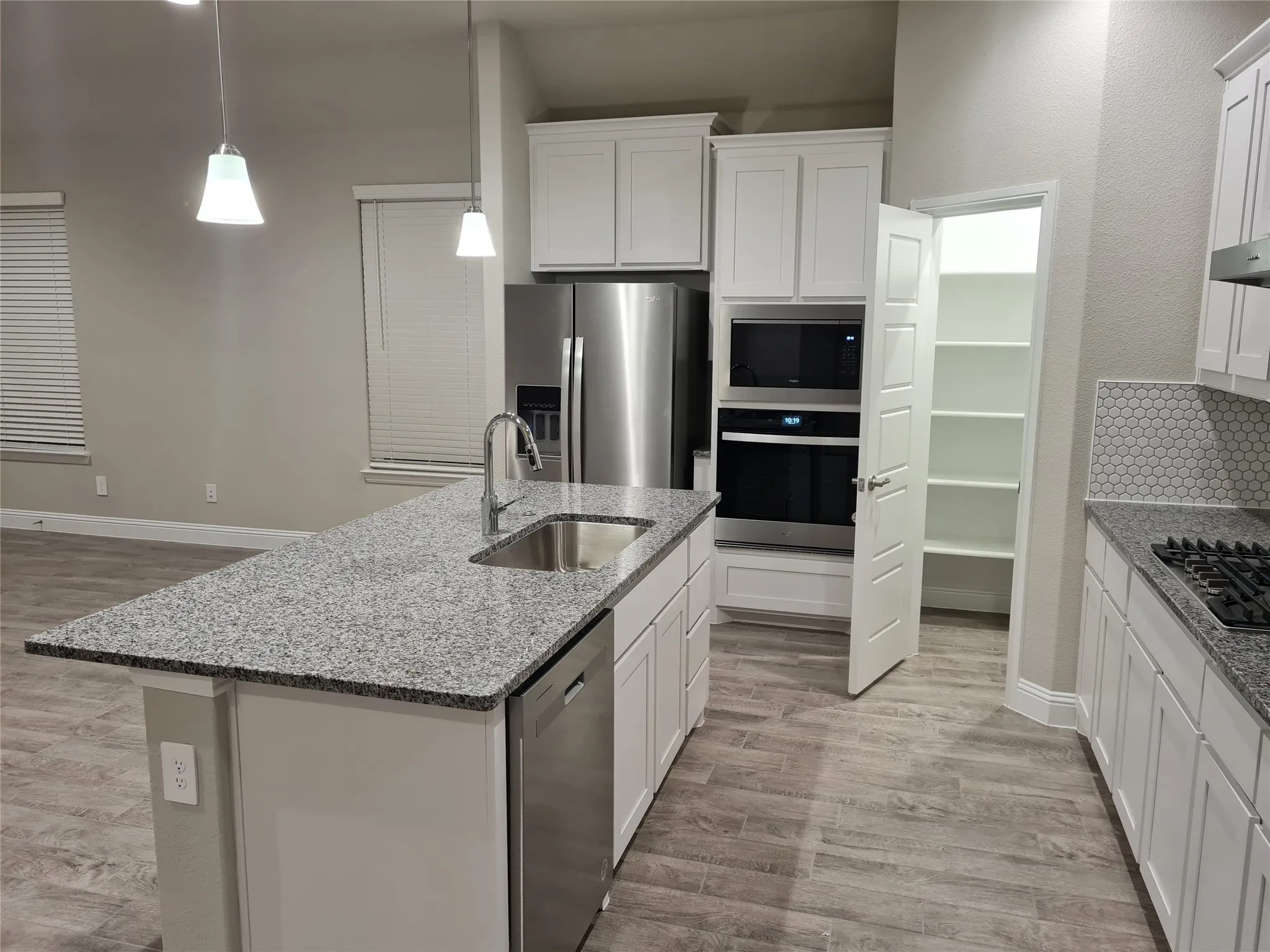 View of Kitchen with the large Granite Island with large stainless steel farmhouse style kitchen sink, Stainless steel appliances: Dishwasher, Microwave, Electric Oven and Refrigerator included with lease.