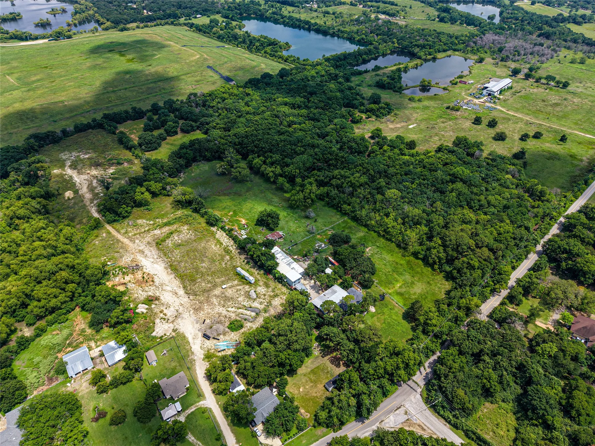 Expansive rural landscape featuring a mix of mature tree cover, open fields, and multiple bodies of water