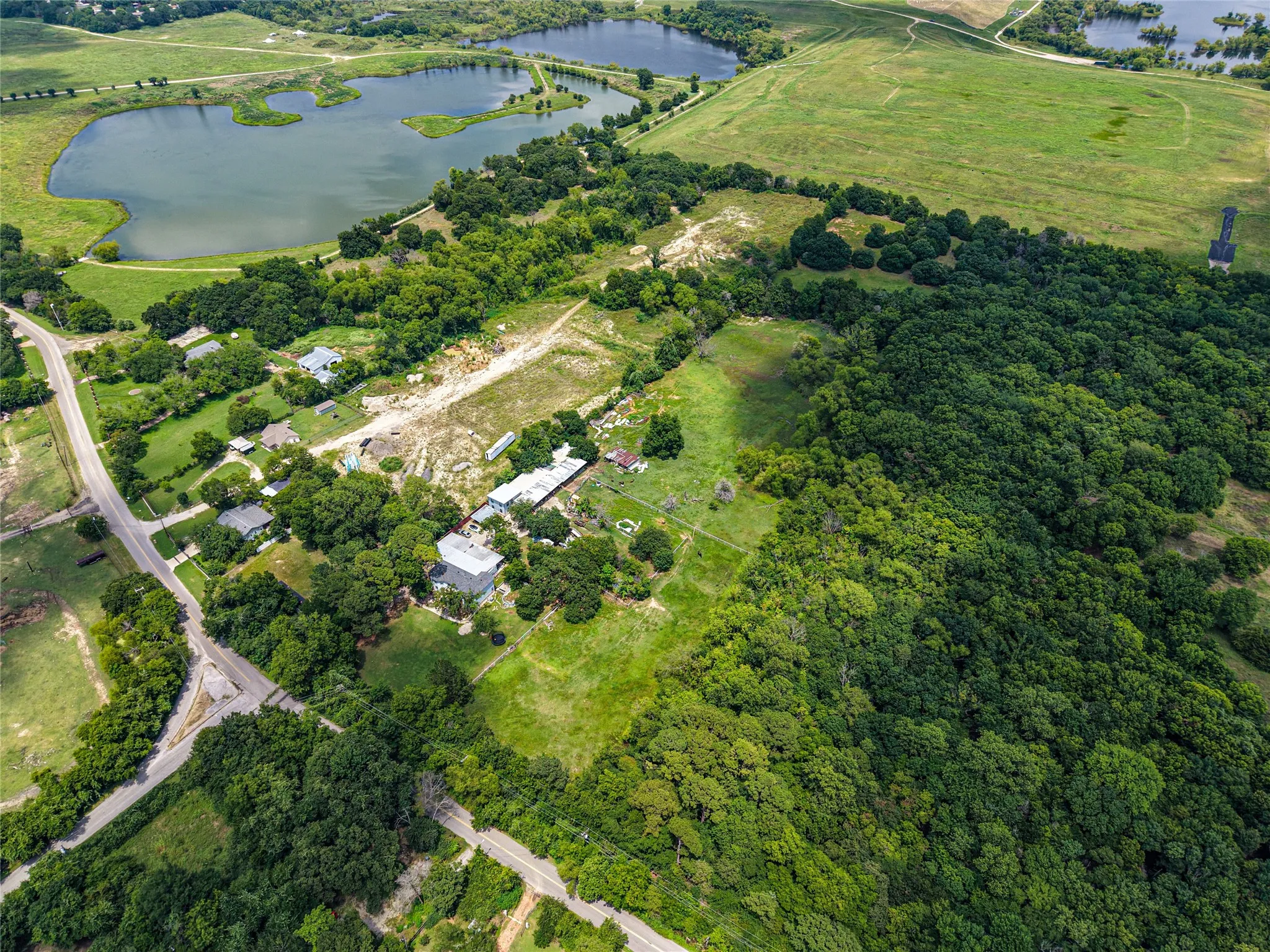 Aerial perspective showcasing expansive green spaces, mature tree coverage, and a substantial body of water
