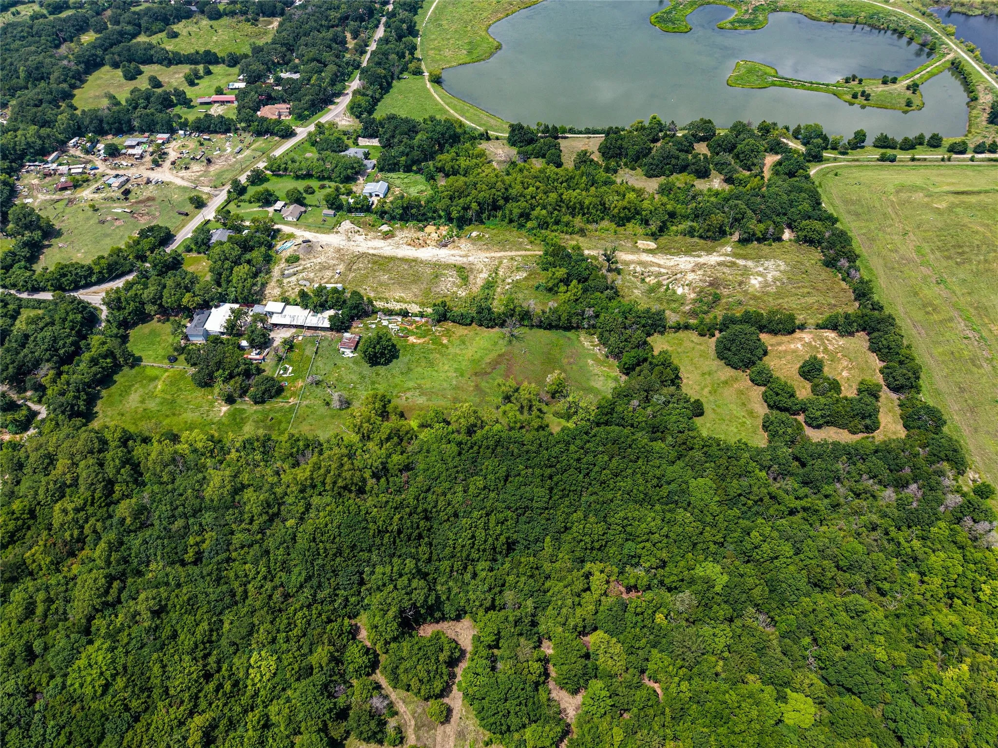 Expansive aerial perspective showcasing diverse terrain including wooded areas, open fields, and a significant body of water