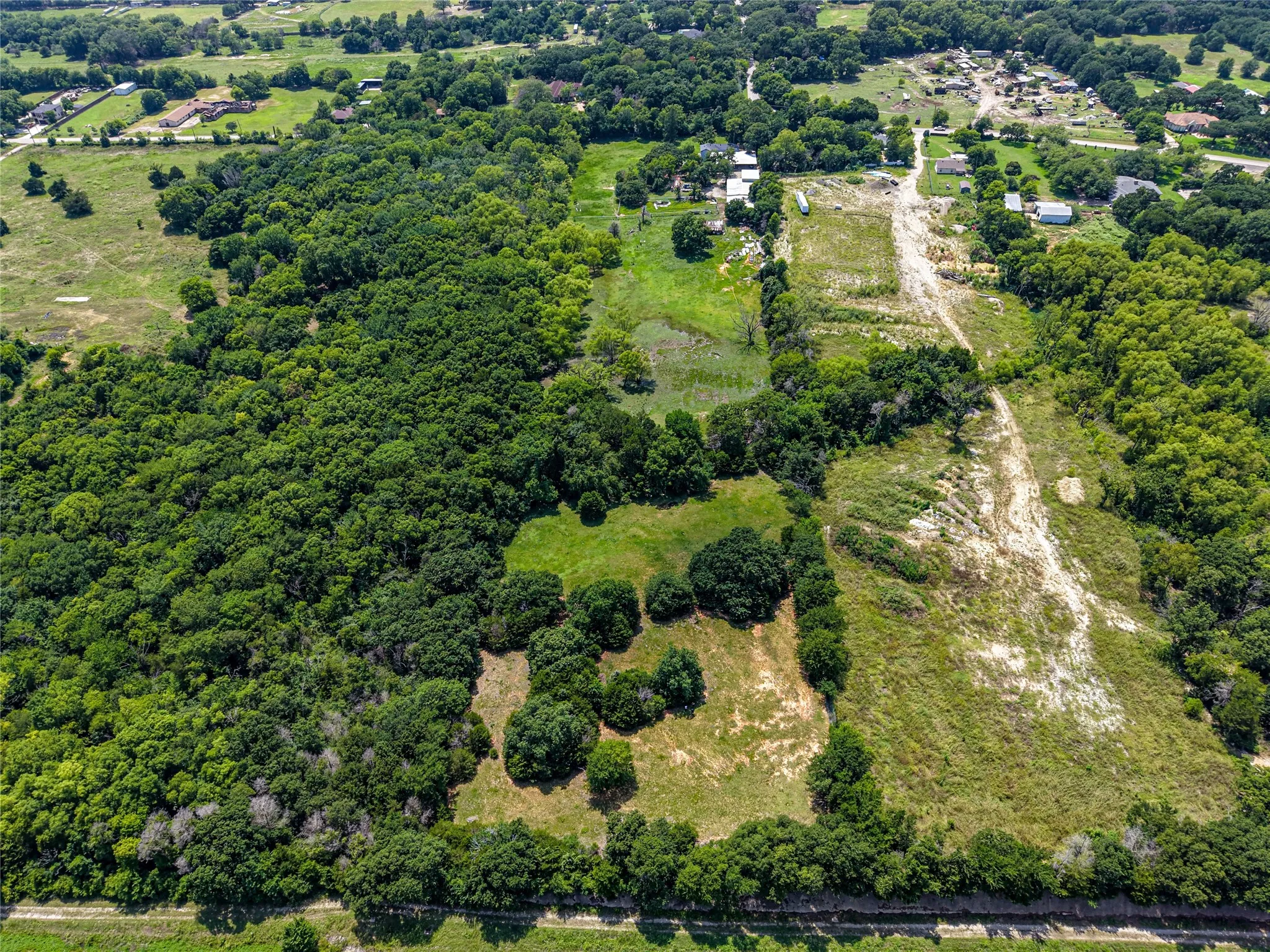 Expansive land parcel featuring dense tree coverage, open grassy areas, and cleared sections
