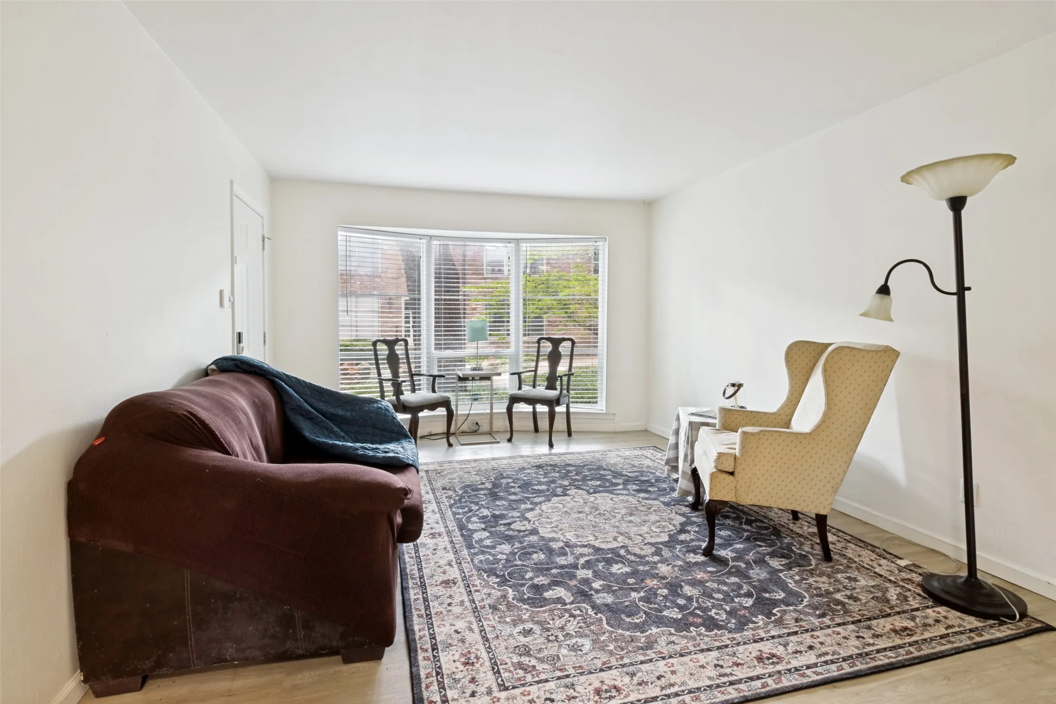 Light-filled interior space featuring a prominent bay window with horizontal blinds