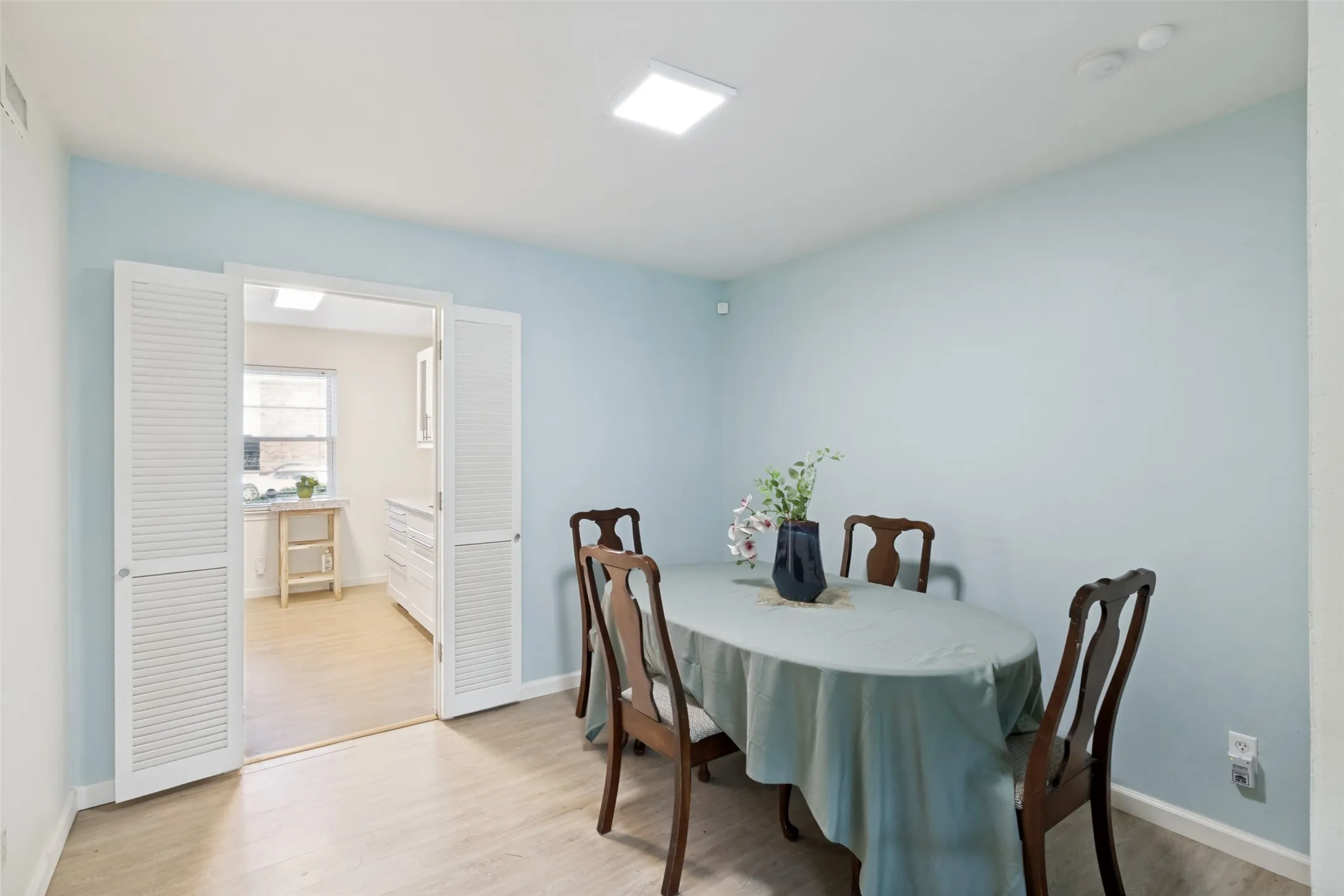 Dining area with light blue walls and wood-finish flooring
