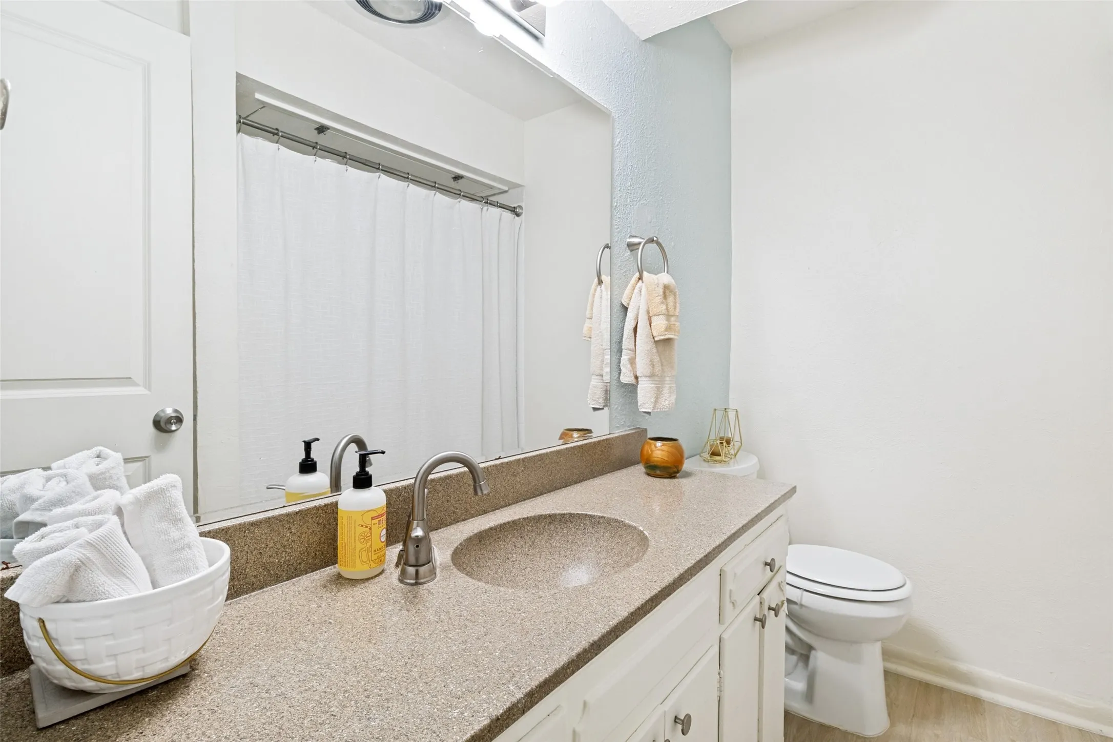 Bathroom featuring a vanity with an integrated sink, a speckled countertop, and white cabinetry