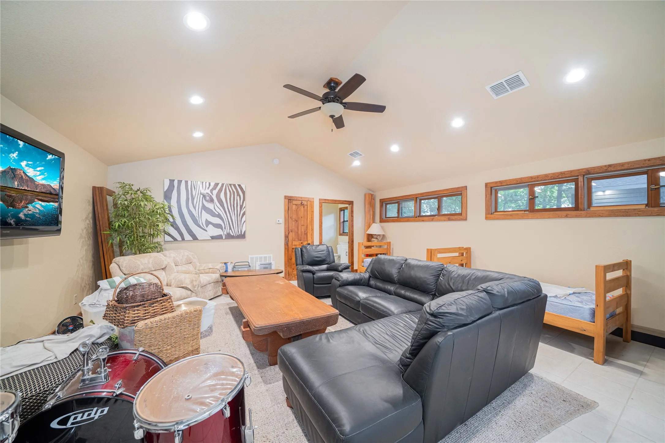 Living room with lofted ceiling, a ceiling fan, recessed lighting, and light tile patterned flooring