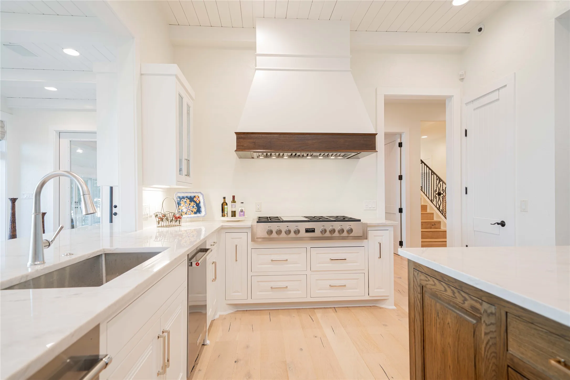 Kitchen featuring appliances with stainless steel finishes, light wood finished floors, premium range hood, white cabinetry, and recessed lighting