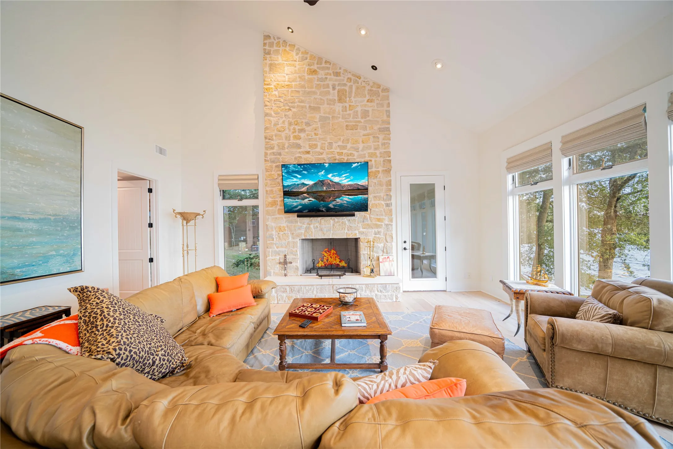 Living area with high vaulted ceiling, a stone fireplace, wood finished floors, and recessed lighting