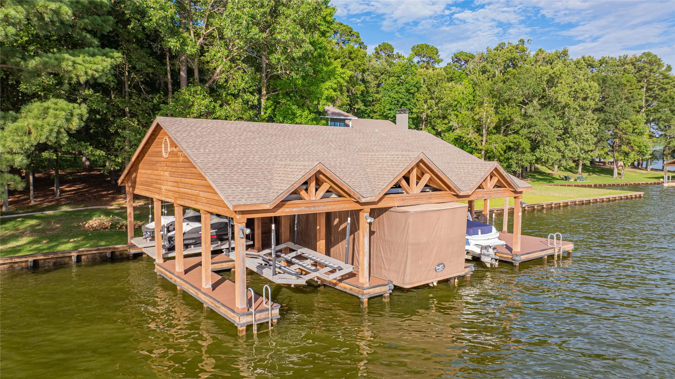 Dock featuring boat lift, a water view, and view of scattered trees