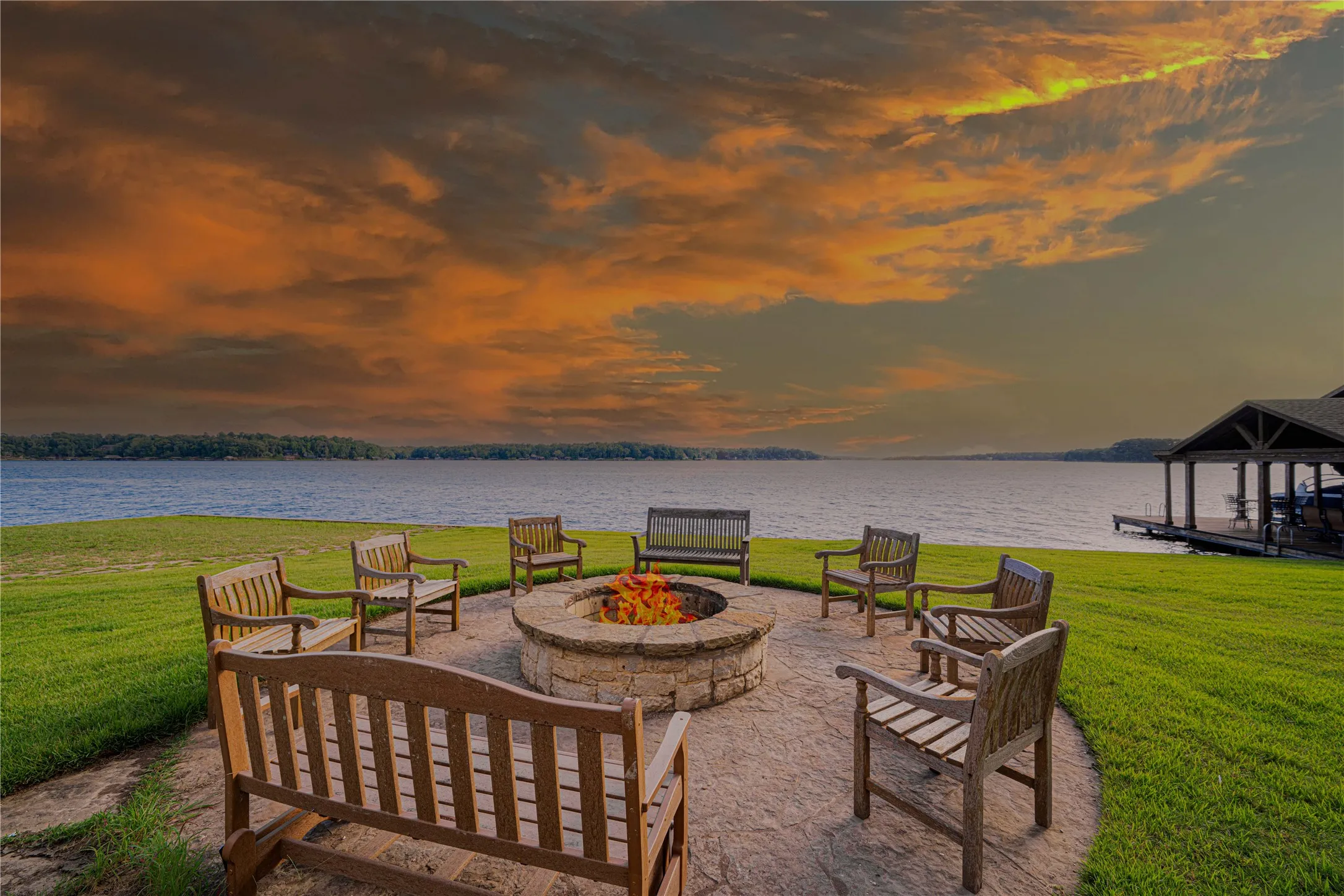 Patio terrace at dusk featuring an outdoor fire pit, a yard, and a water view