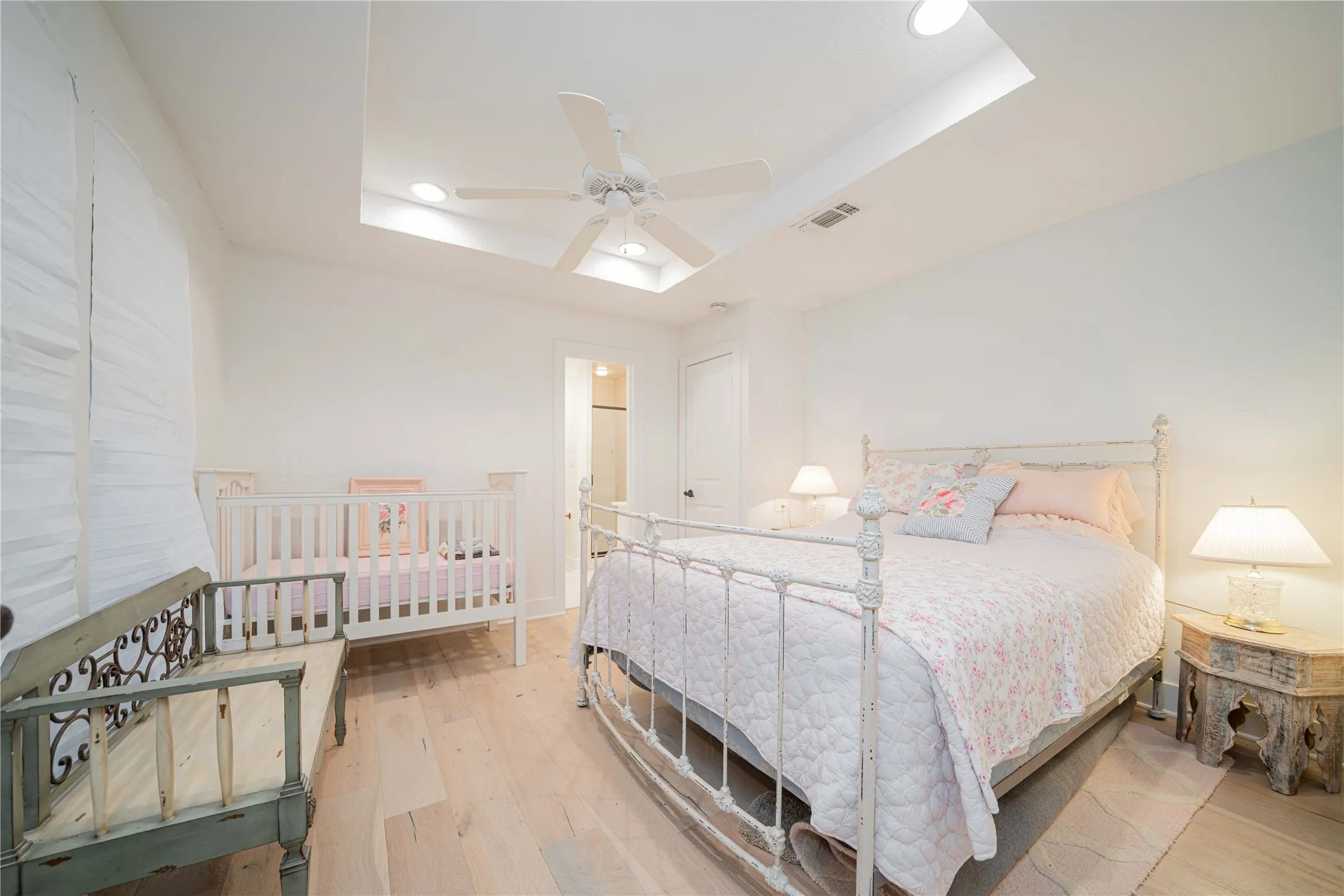 Bedroom with a raised ceiling, wood finished floors, recessed lighting, and ceiling fan