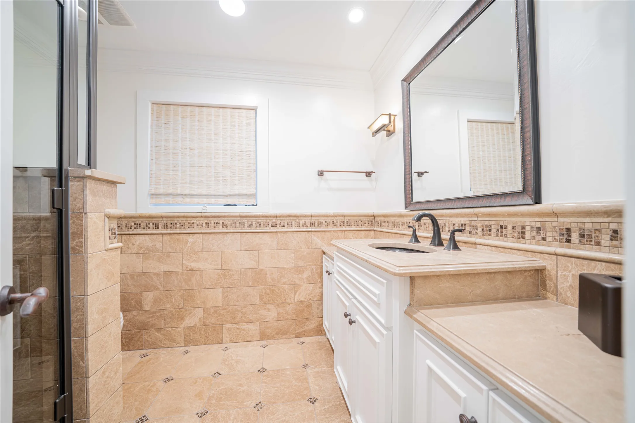 Bathroom with tile walls, vanity, wainscoting, a shower stall, and crown molding