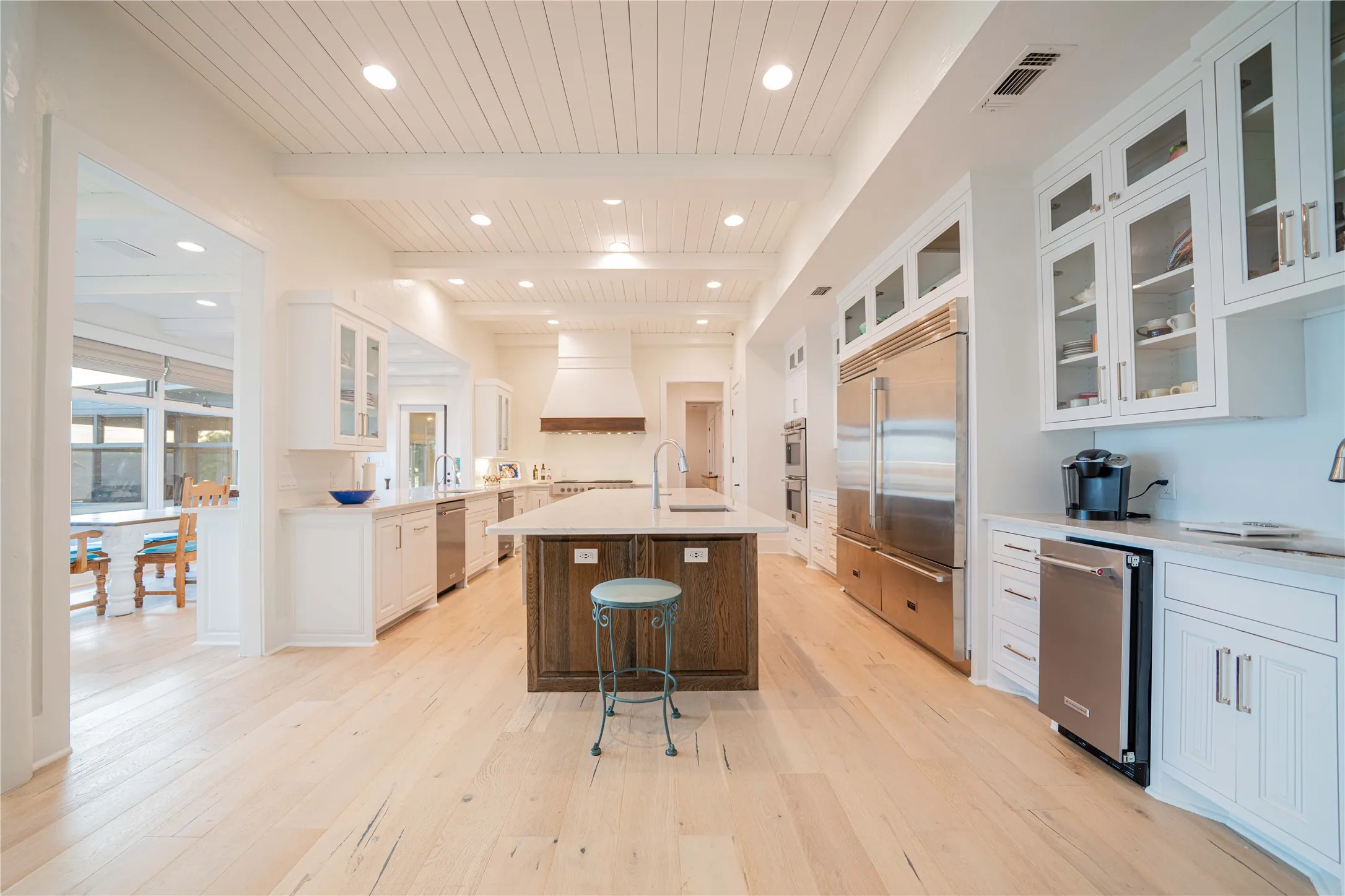 Kitchen featuring appliances with stainless steel finishes, light wood-type flooring, premium range hood, light countertops, and recessed lighting