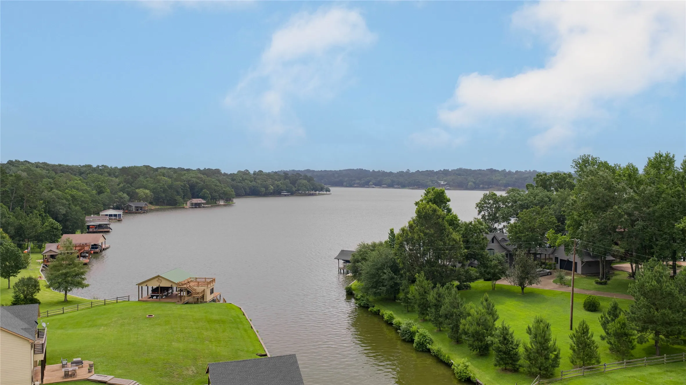Expansive lakefront property featuring a private boat dock with covered slip, direct water access, a spacious grassy lawn, and mature trees