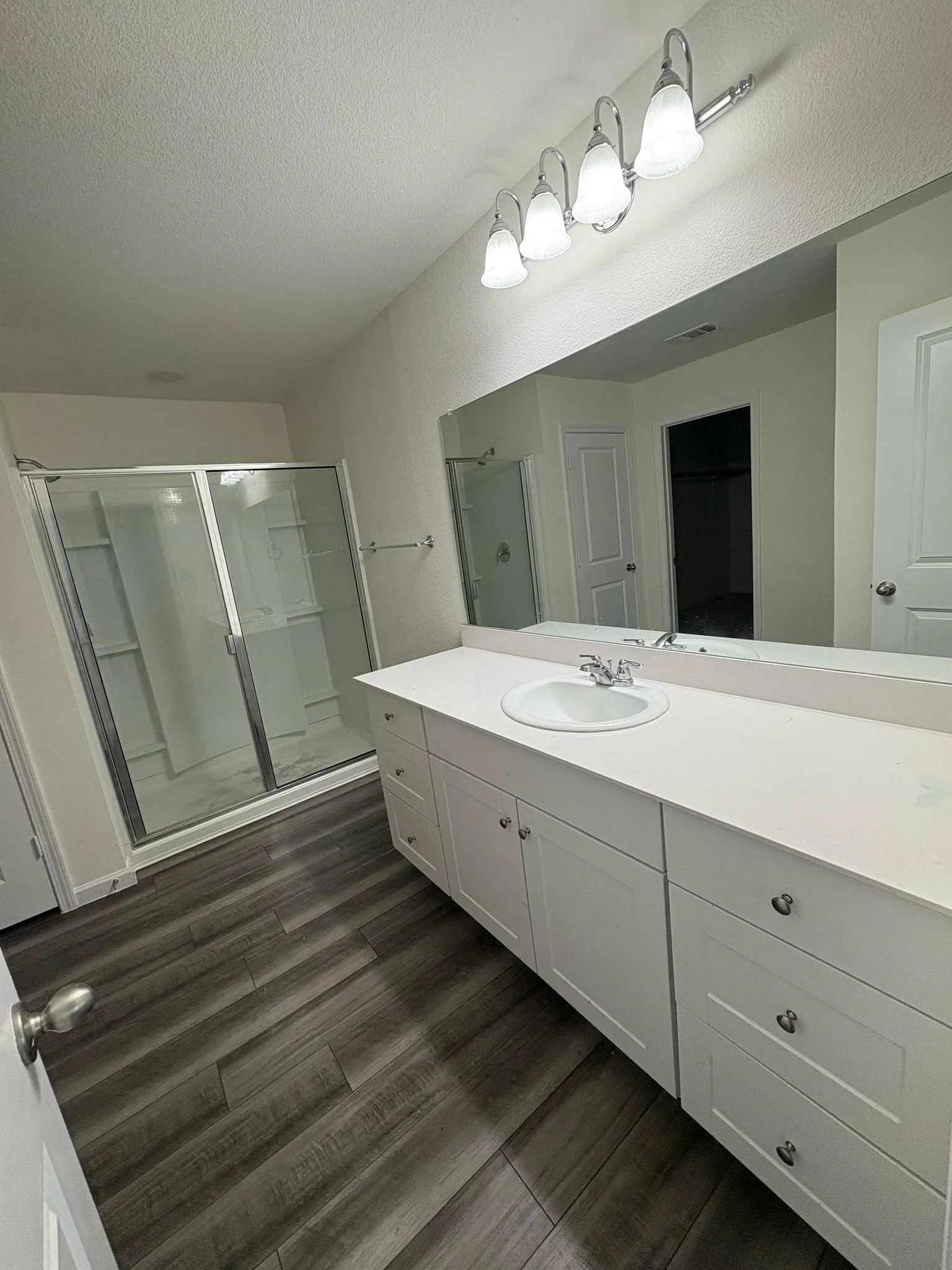Bathroom featuring an extended white vanity with integrated sink, coordinating countertop, and ample storage cabinetry