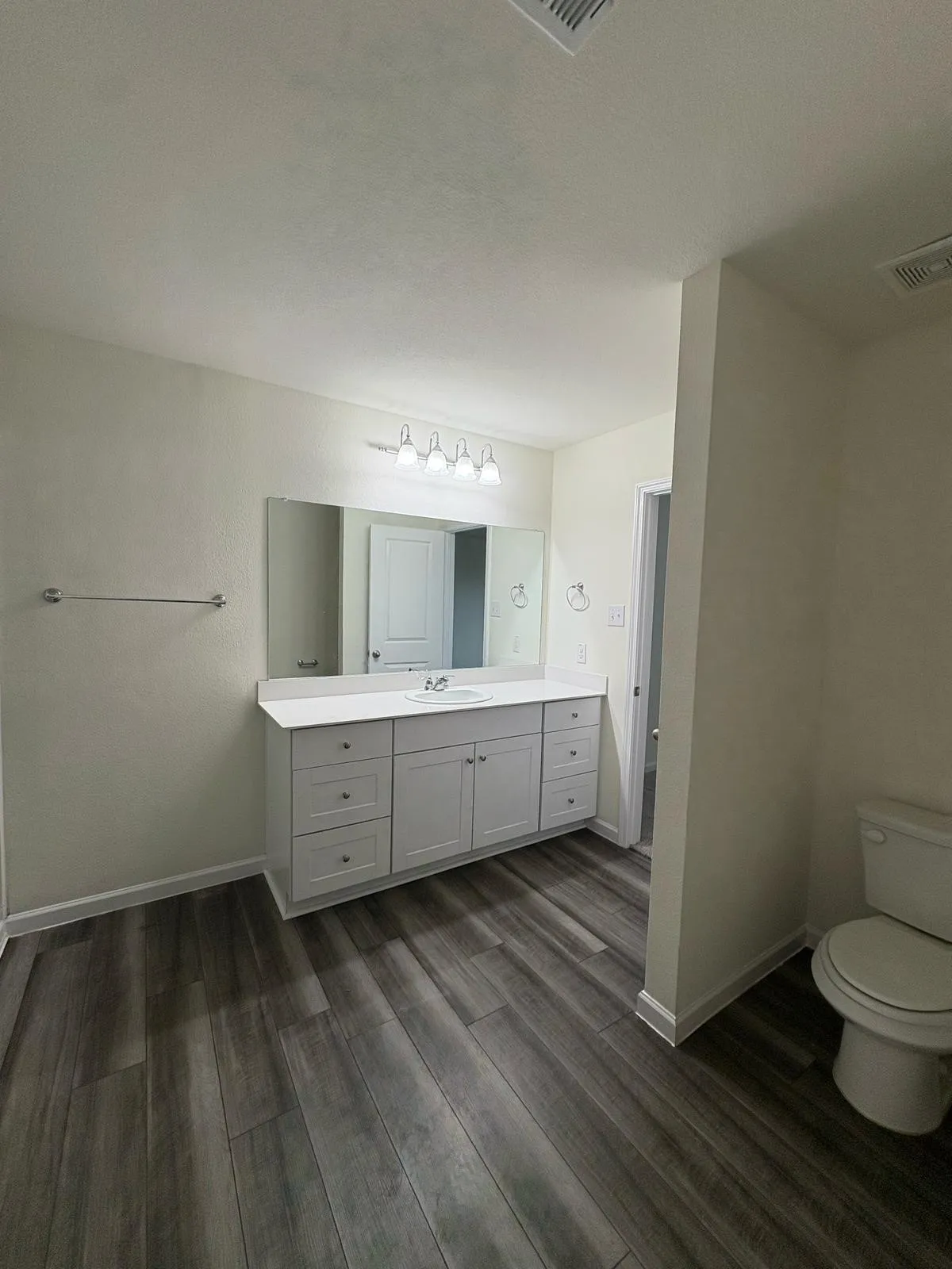 Spacious bathroom featuring an extended vanity with white cabinetry, a single basin sink, and a large mirror