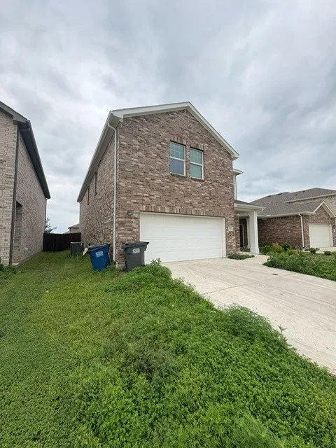 Two-story brick exterior with white trim, a two-car garage, and a concrete driveway