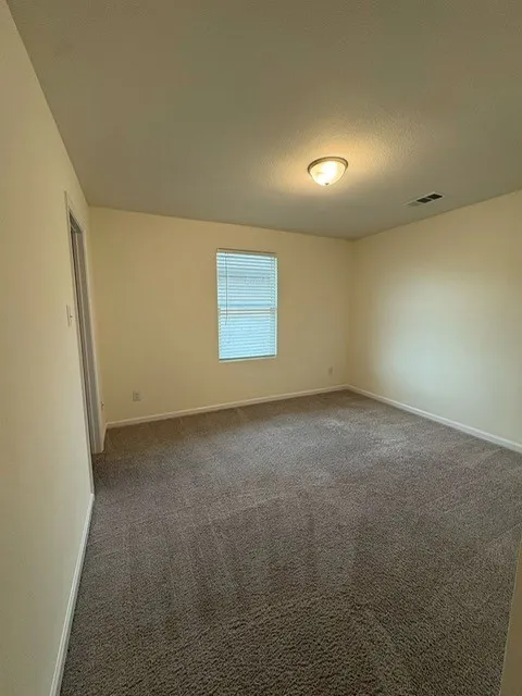 Carpeted room with a single window featuring horizontal blinds