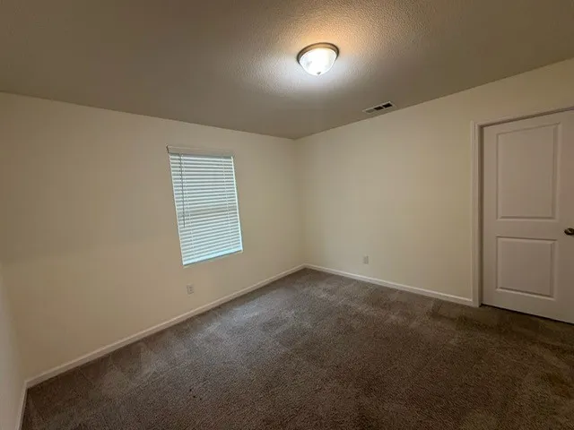 Neutral-toned interior room featuring light beige walls and a brown textured carpet