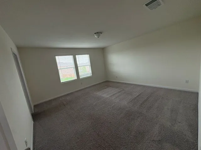 Spacious room featuring neutral carpeting, light-toned wall paint, white trim, and two windows with blinds