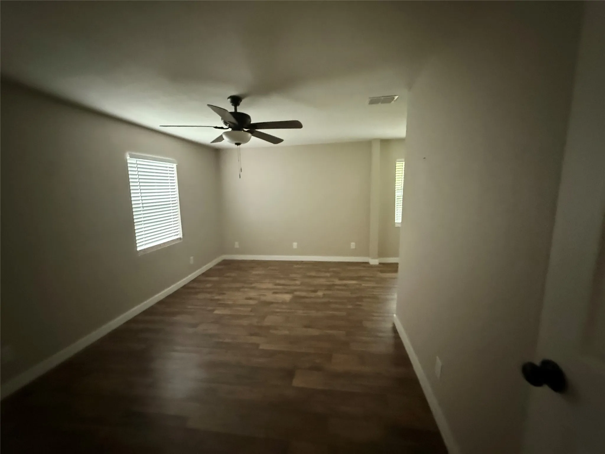 Expansive room featuring wood-finish flooring, neutral paint palette, and white baseboards