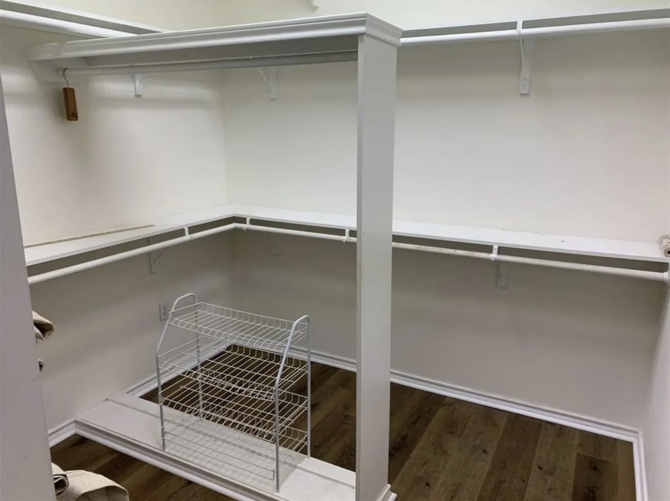 Walk-in closet featuring wood-finish flooring, white walls, multiple shelving units, and ample hanging rods for organization