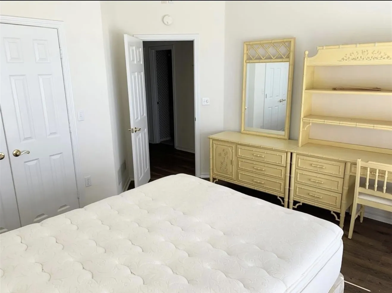 Interior space featuring light-colored walls, wood-finish flooring, and white paneled doors with gold-tone hardware
