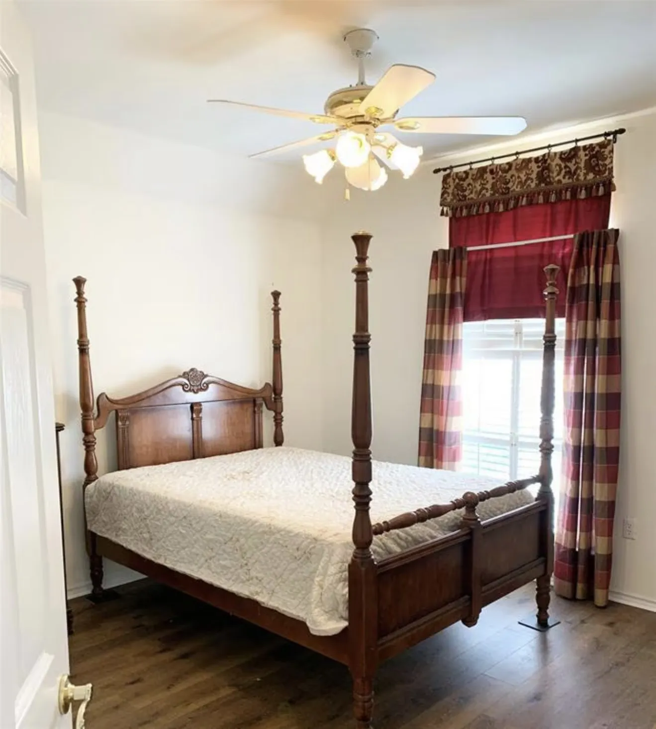 Interior room featuring a ceiling fan with integrated lighting, wood-finish flooring, and window treatments with valance