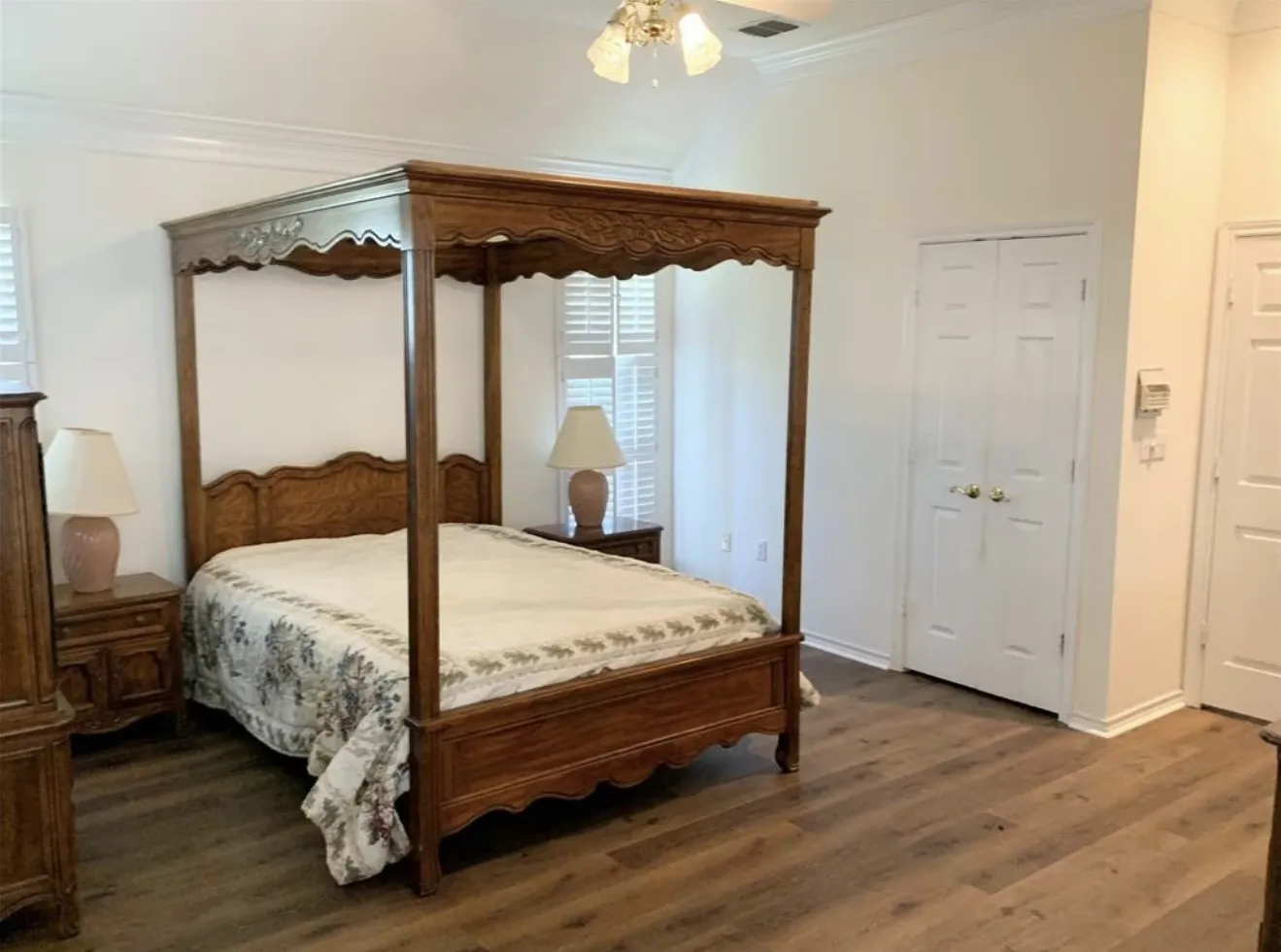 Vaulted ceiling room featuring wood-finish flooring, plantation shutters, and a ceiling fan with light fixture