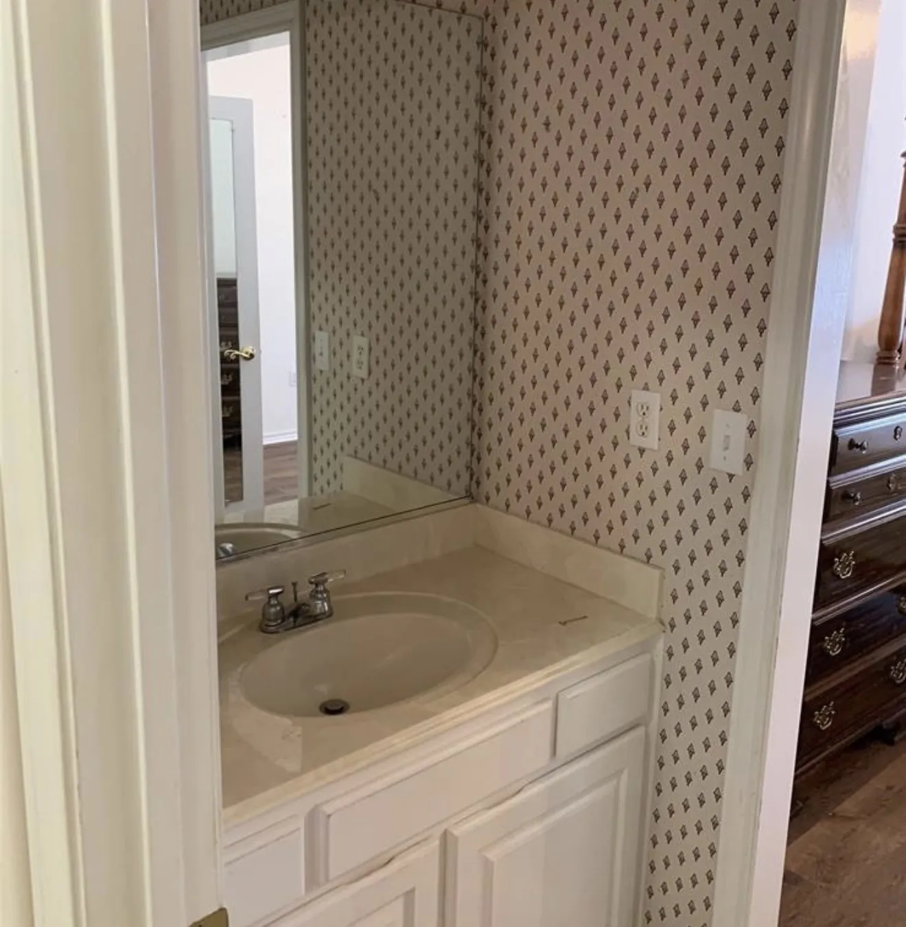 Vanity area featuring a white cabinet base, an integrated sink, and an expansive wall mirror