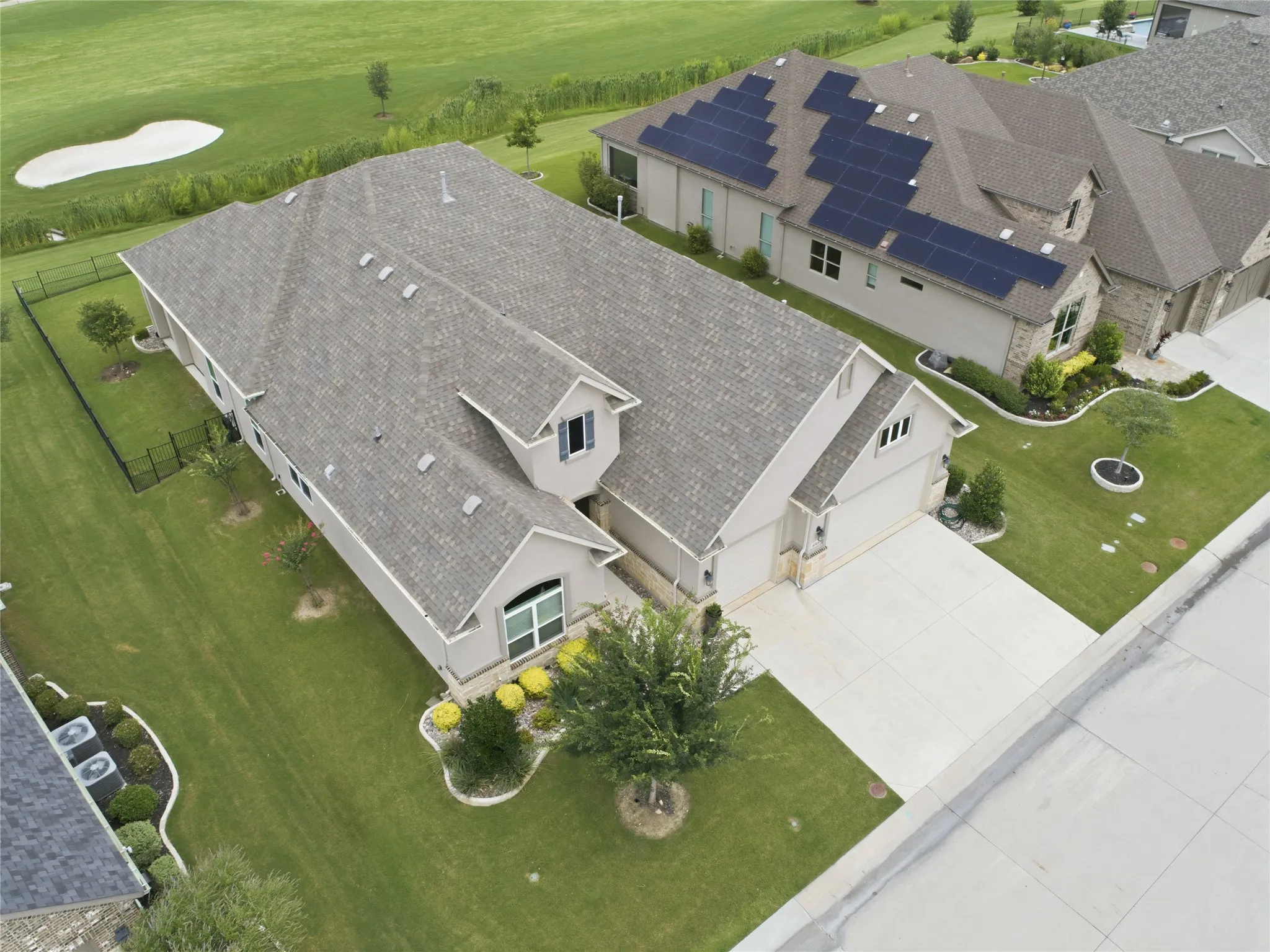 Contemporary residence featuring a paved driveway, attached garage, and manicured landscaping