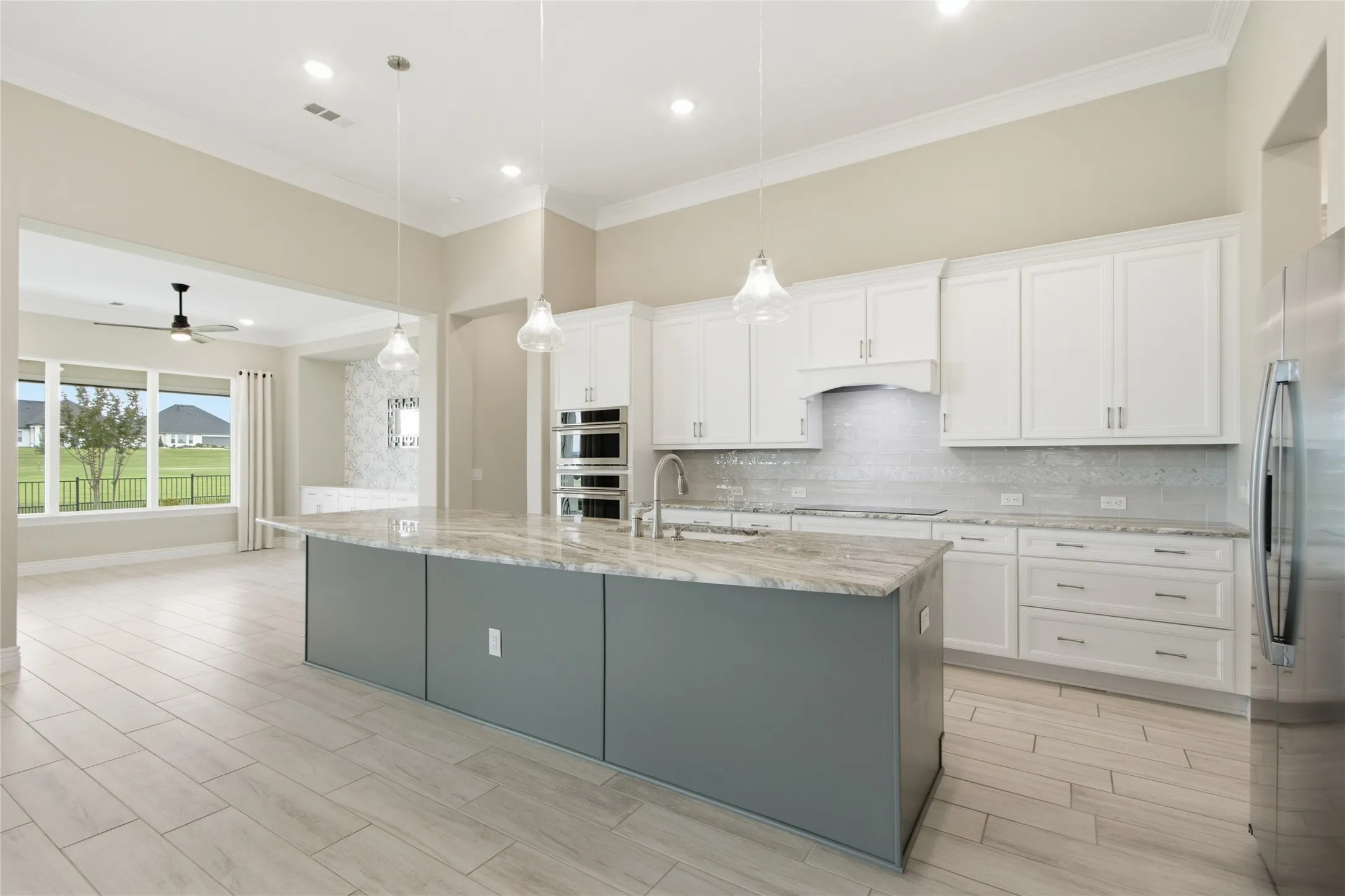 Gourmet kitchen featuring a large island with a stone countertop, white shaker cabinetry, stainless steel appliances, and wood-finish flooring