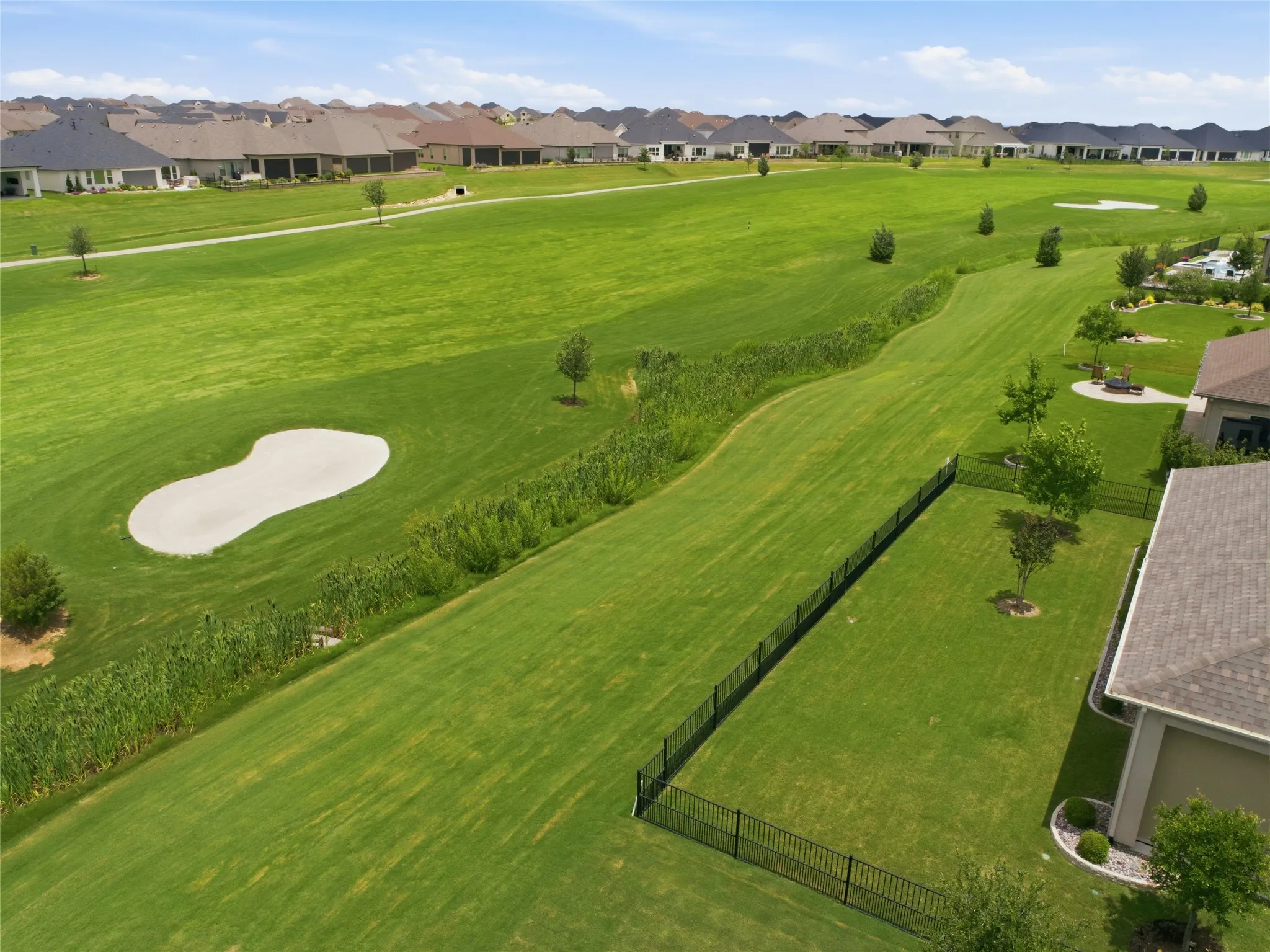 Expansive green space featuring a sand trap, manicured lawn, and mature trees