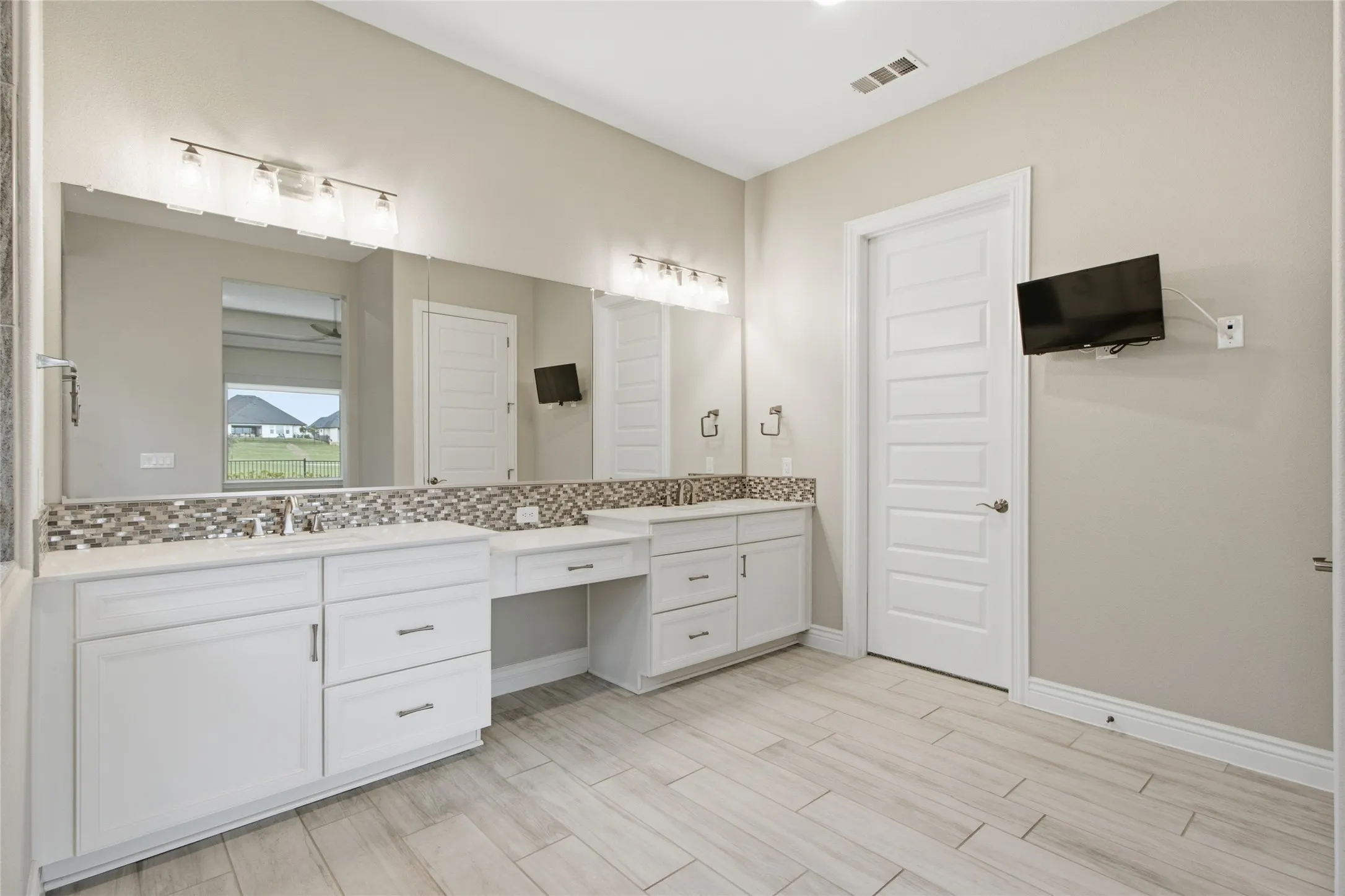 Double vanity with white cabinetry, ample counter space, and a mosaic tile backsplash