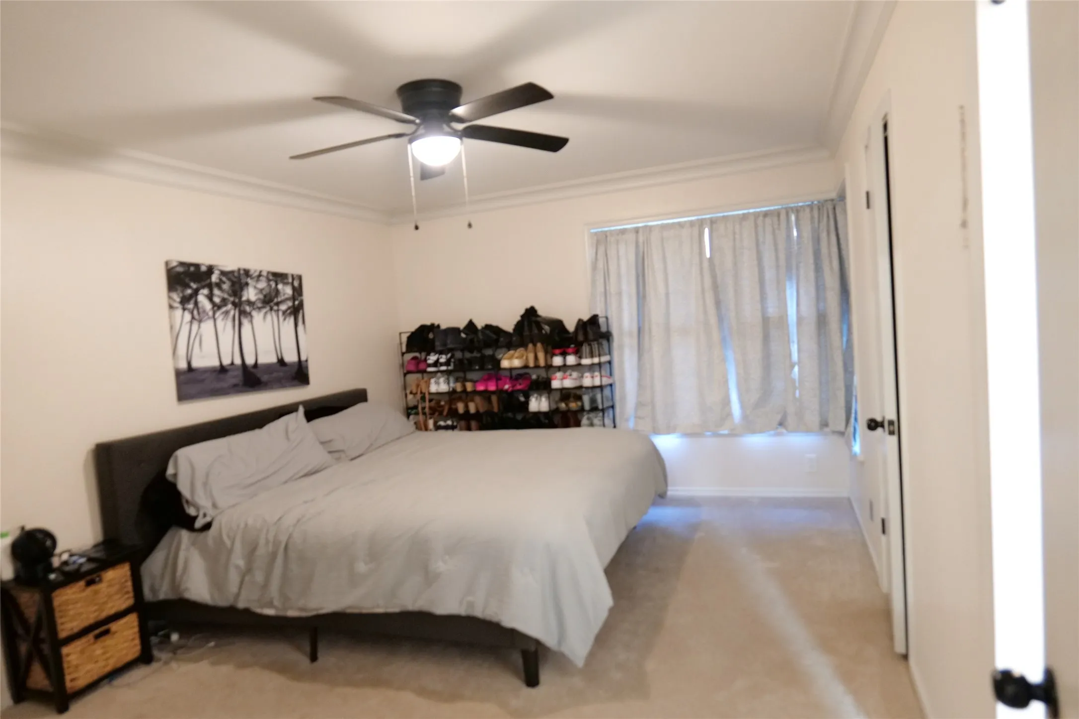 Bedroom featuring neutral wall paint, crown molding, a ceiling fan with integrated lighting, a window with curtains, and carpet flooring