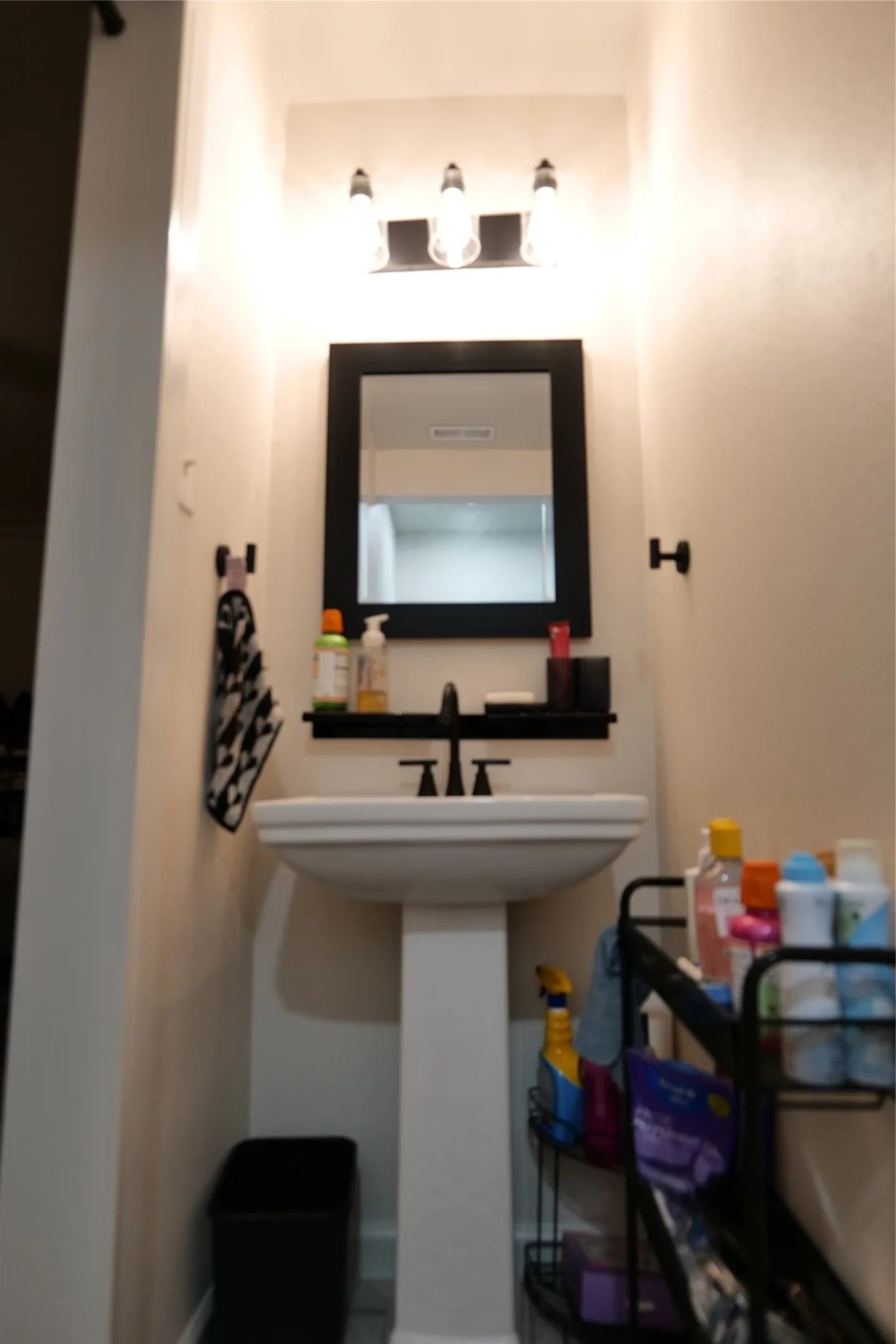 Pedestal sink with black hardware and a coordinating wall-mounted mirror