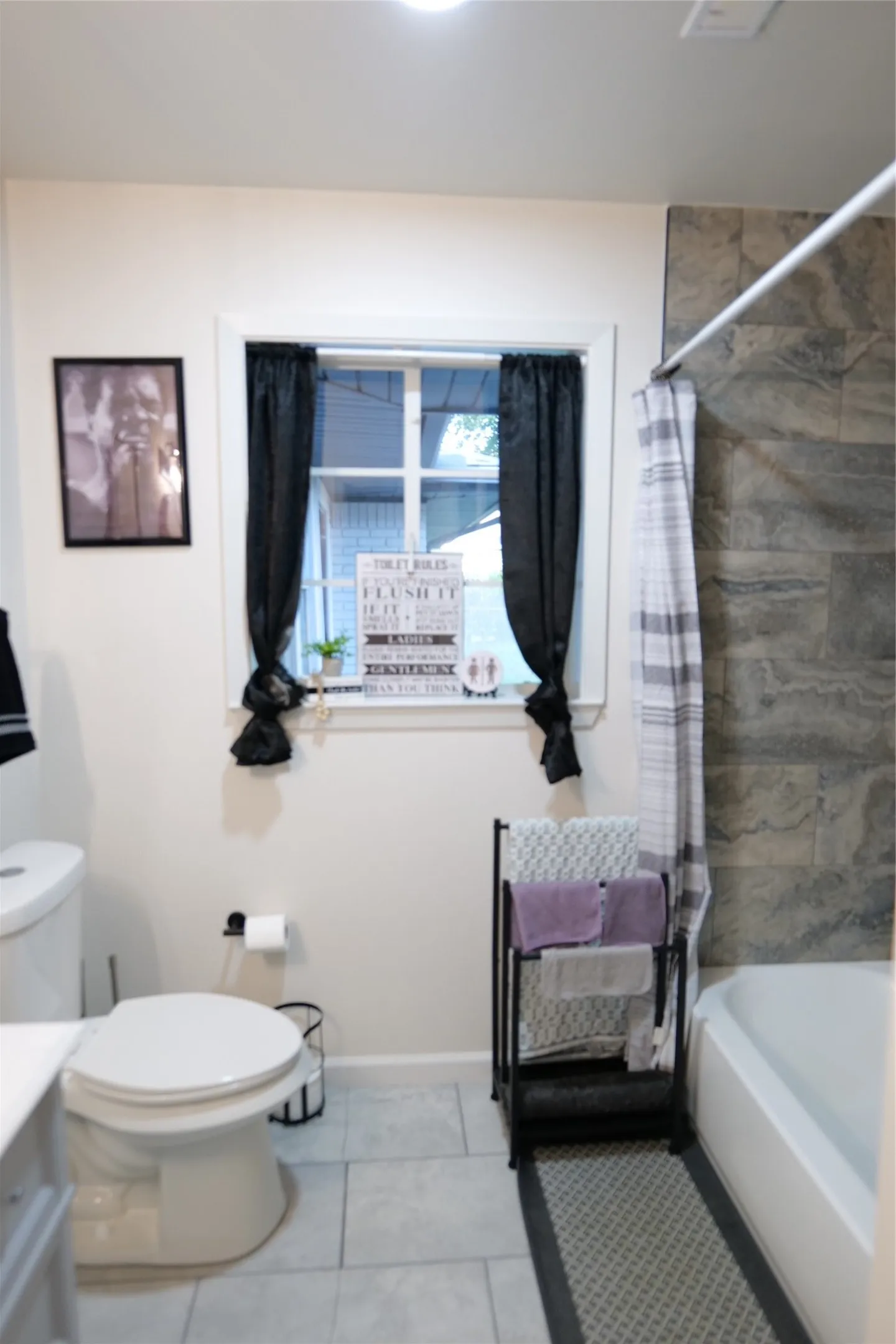 Bathroom featuring a full tub with shower, contemporary wall tiling, and light-toned floor tiles