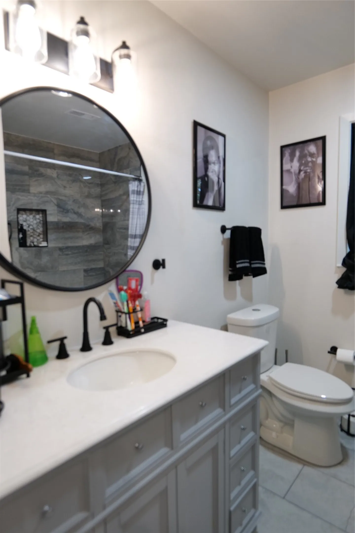 Bathroom featuring a vanity with a white countertop and undermount sink, matte black faucet, and a round mirror